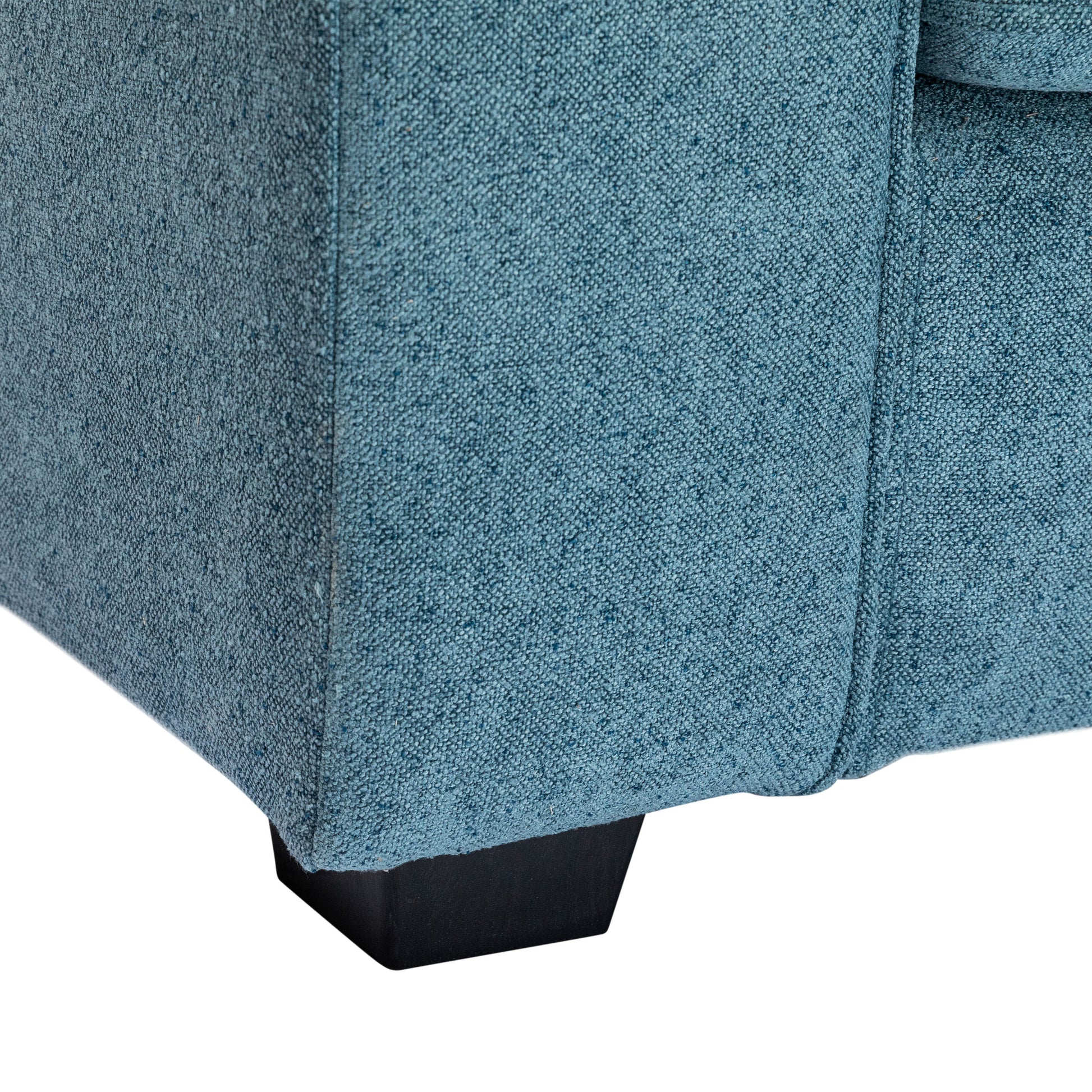 Closeup of a teal textured fabric sofa corner with a black wooden leg perfect for modern living rooms