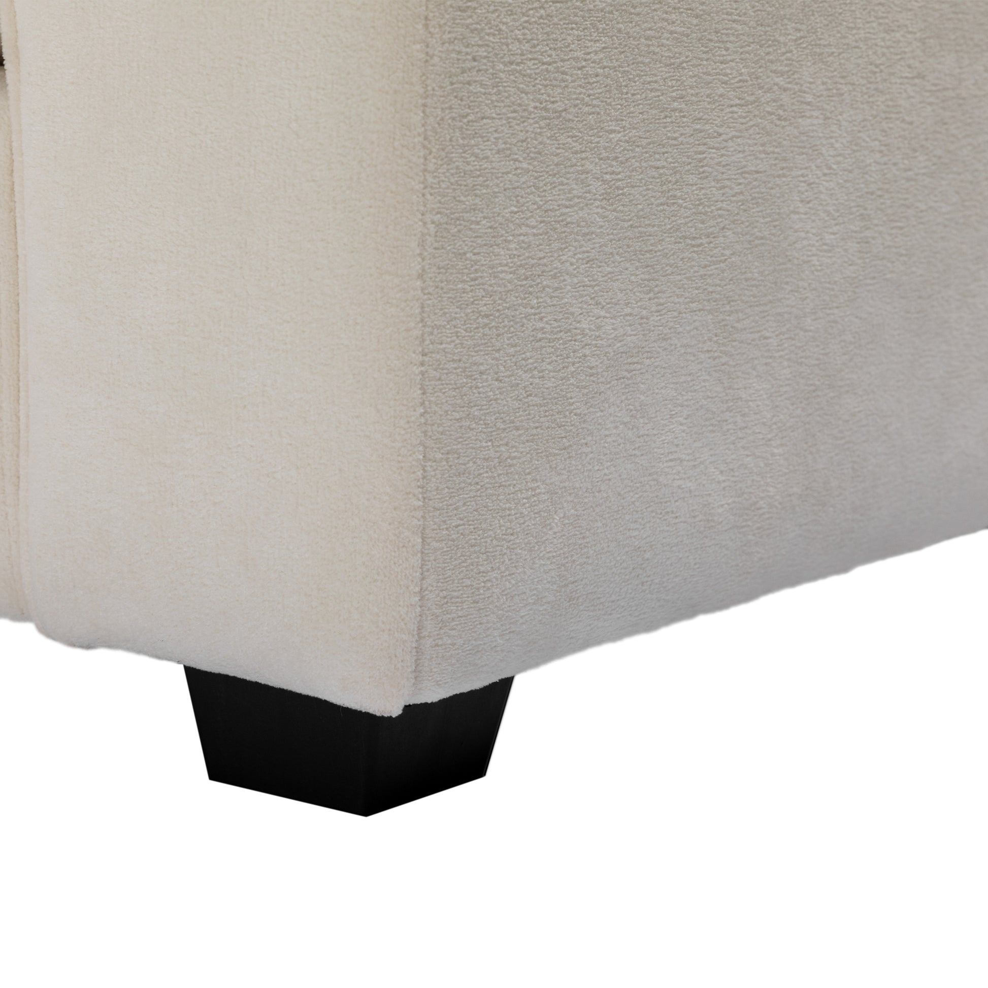 Cream boucle fabric sofa corner detail with black wooden leg