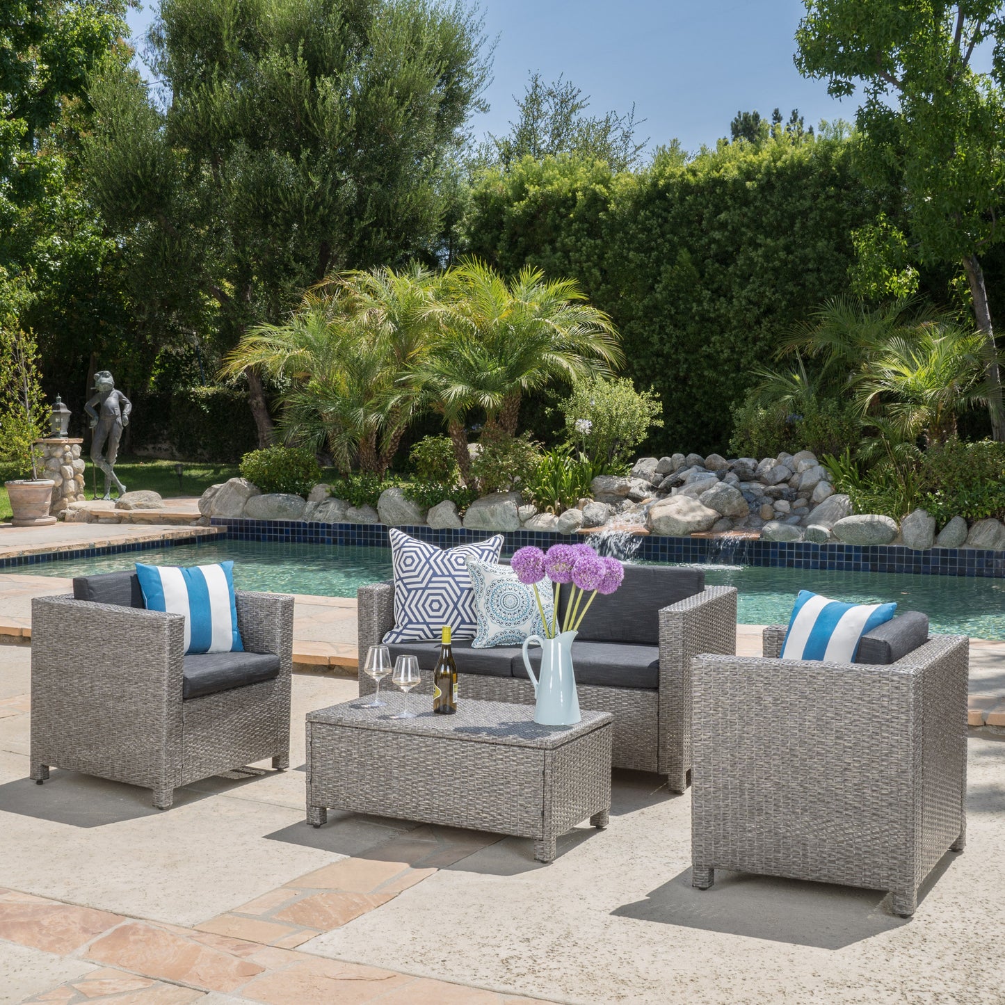 Grey wicker patio furniture set with dark grey cushions by poolside