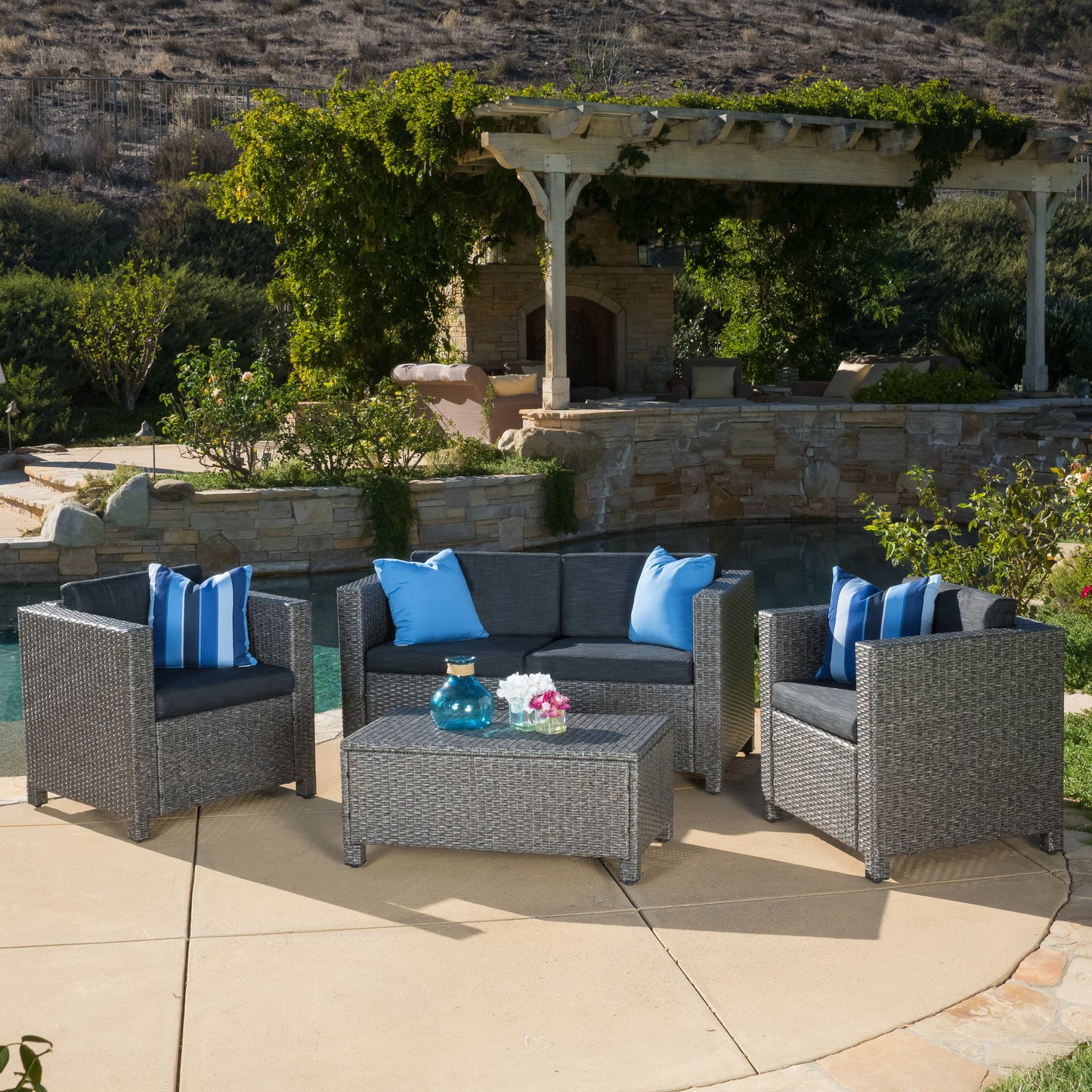 Grey wicker patio sofa set with blue and white striped cushions and blue throw pillows