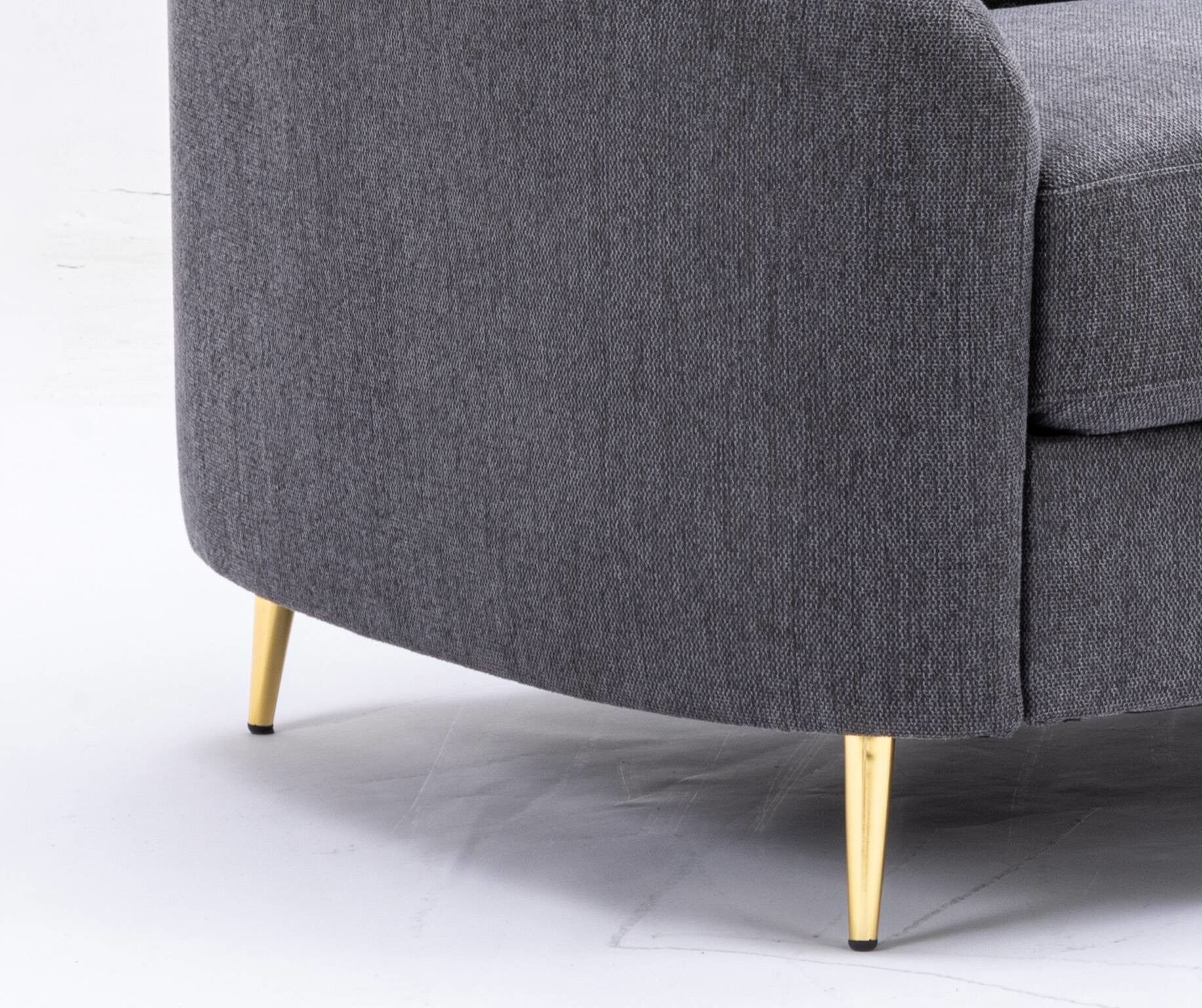 Closeup of textured dark gray fabric sofa with tapered gold legs modern living room furniture