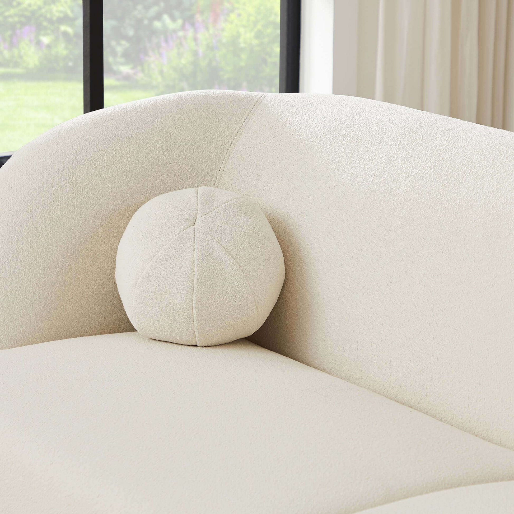 Textured cream throw pillow with stitched panel detail on a matching sofa