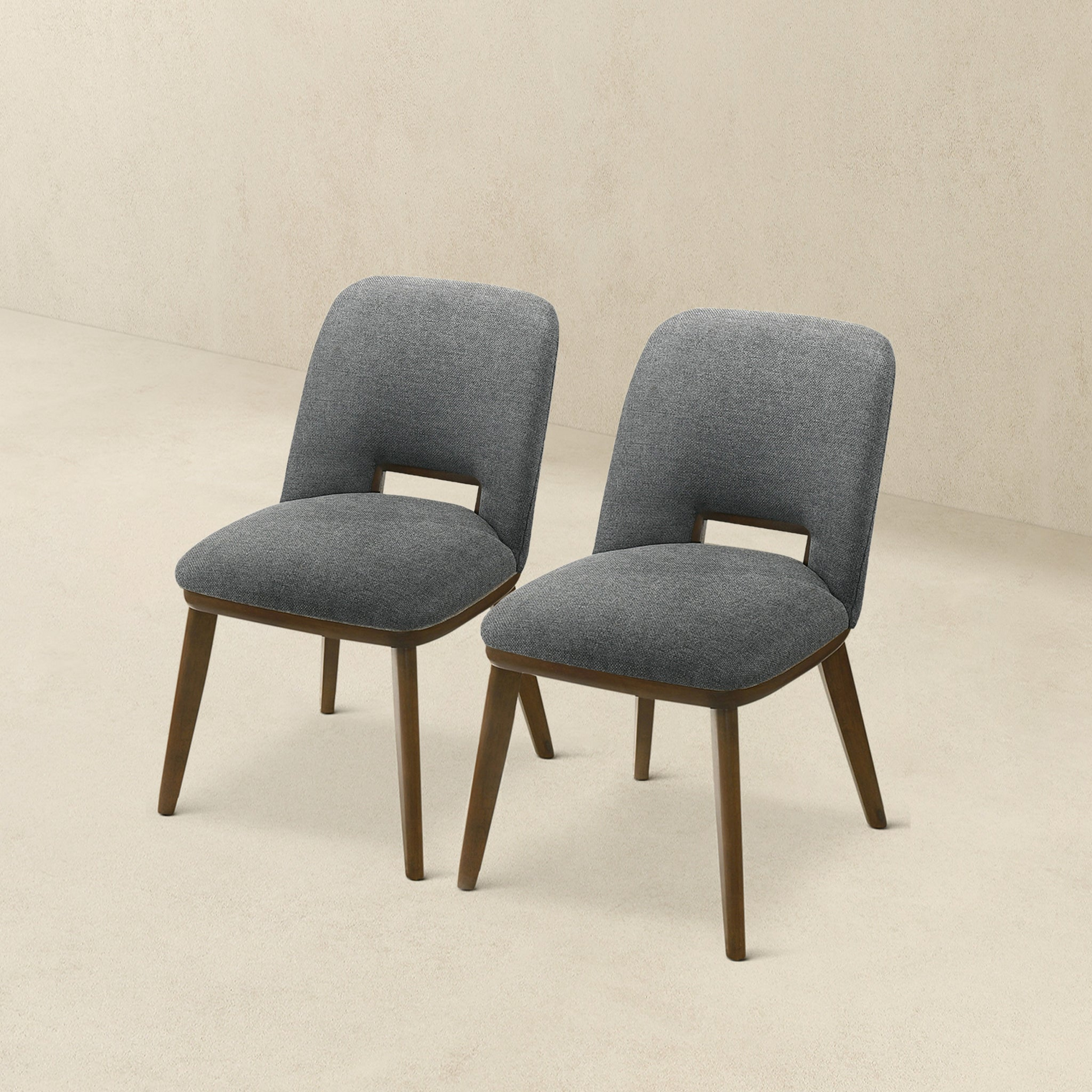 Two grey upholstered dining chairs with wooden legs