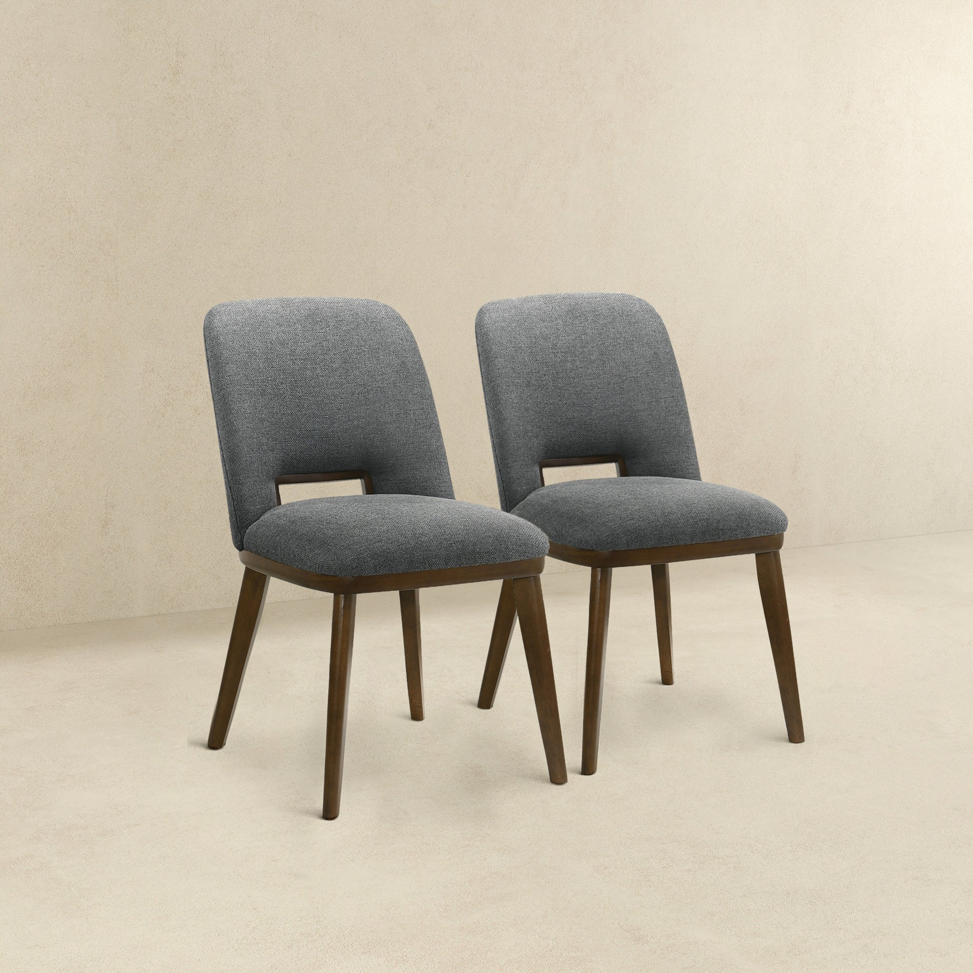Two grey upholstered dining chairs with dark wood legs