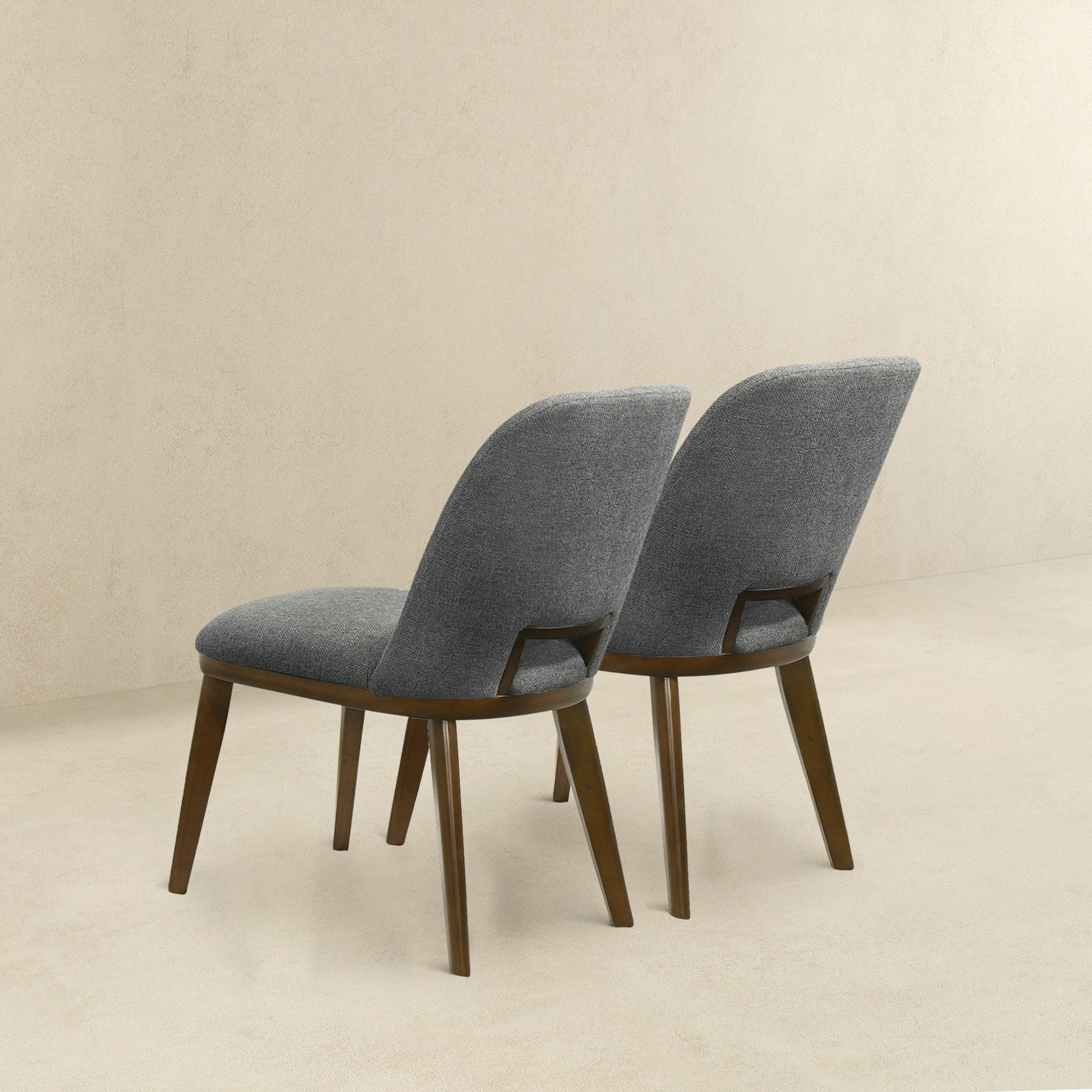 Two upholstered dining chairs with grey fabric and dark wood legs