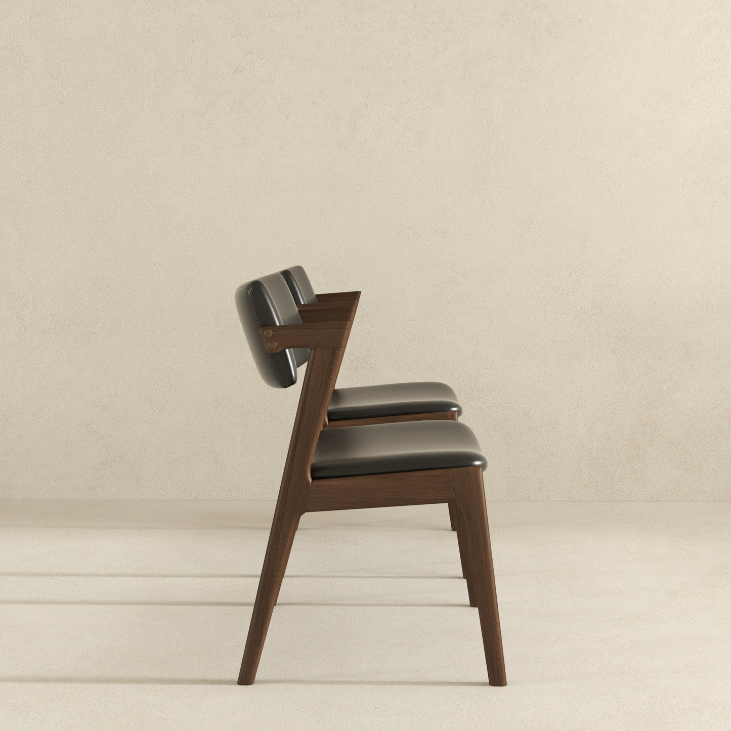 Modern dark wood dining chair with black leather upholstery and sleek silhouette