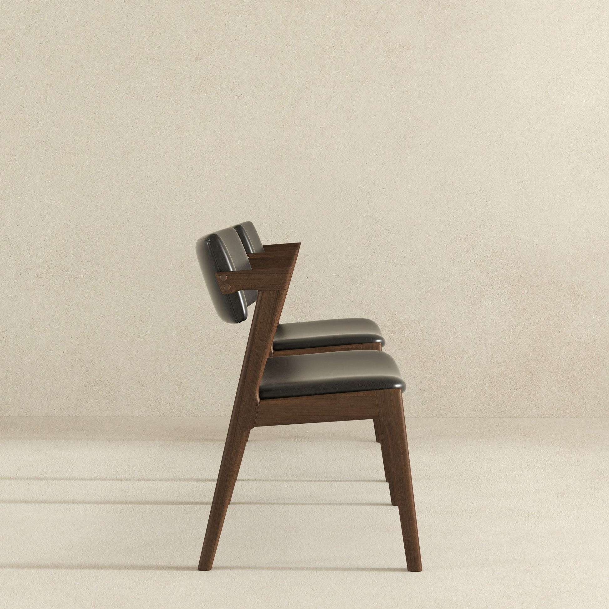 Modern dark wood dining chair with black leather upholstery and sleek silhouette
