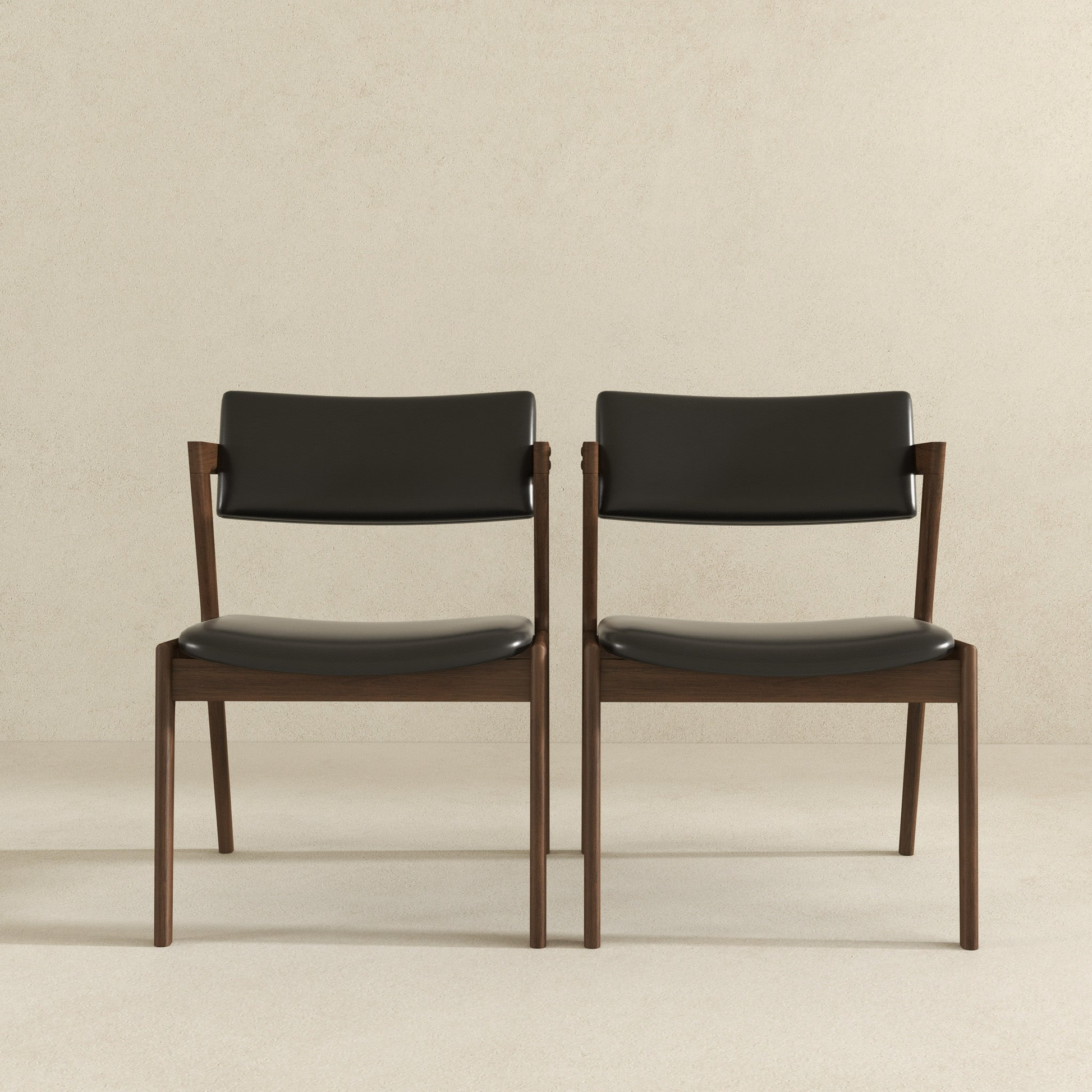 Two modern dark wood dining chairs with black faux leather upholstery