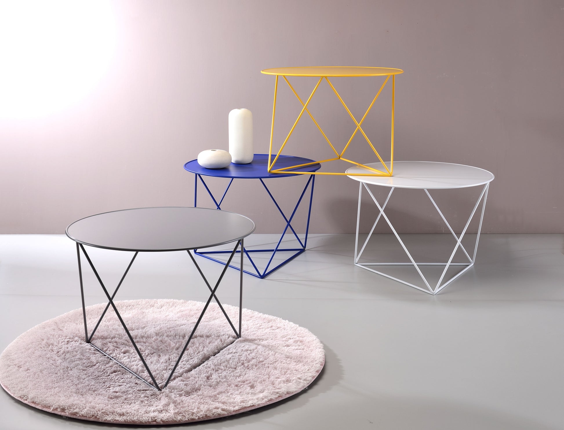 Grey metal side table with a geometric wire base on a fluffy rug