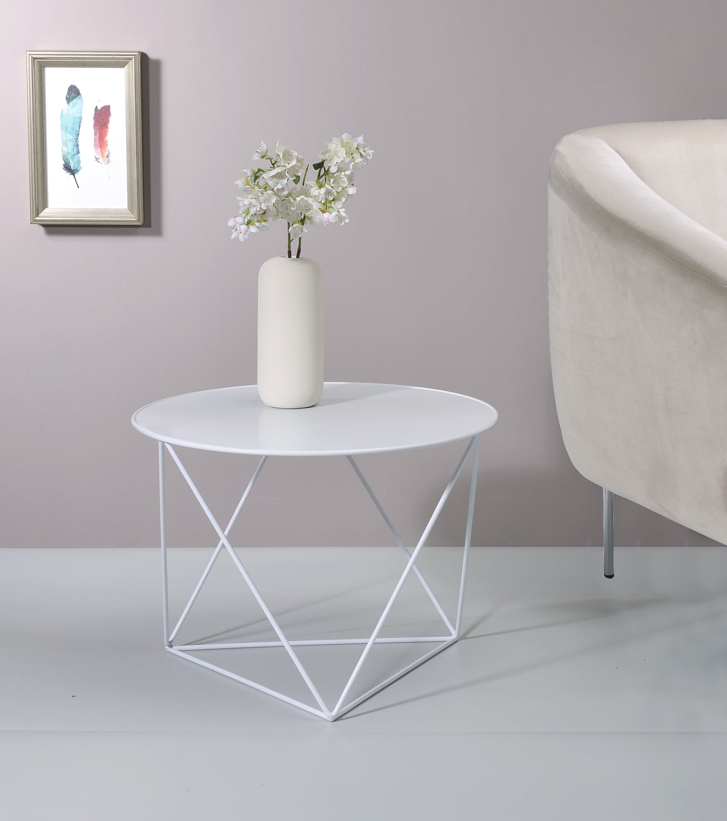 White geometric metal side table with round top holding a vase of white flowers