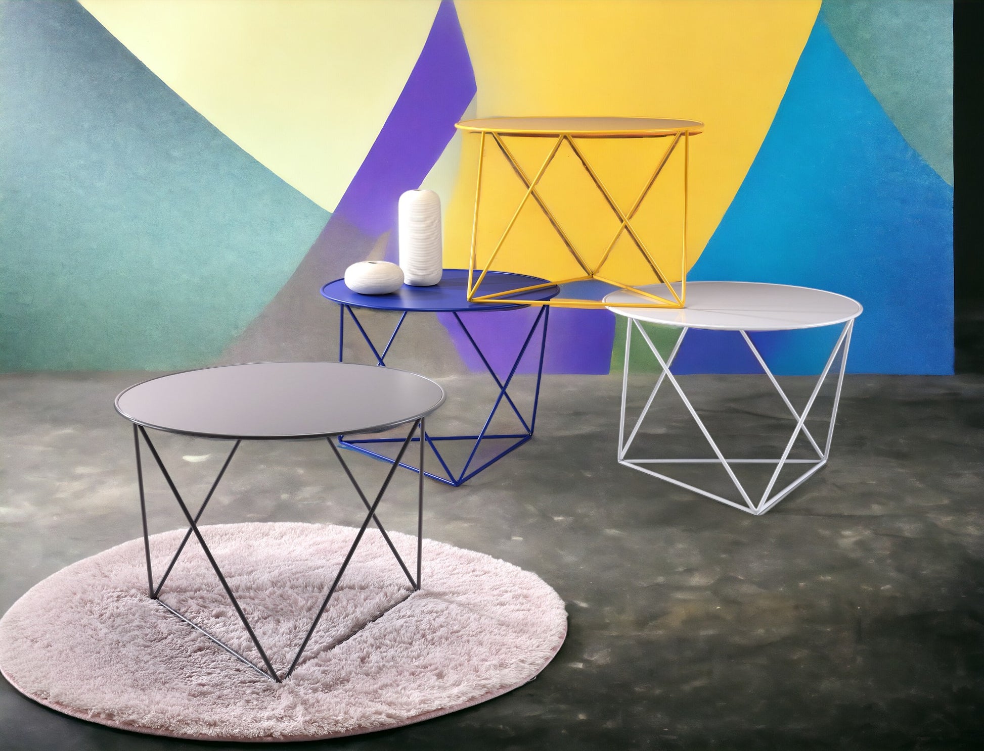 Round grey metal side table with modern black geometric base on plush rug