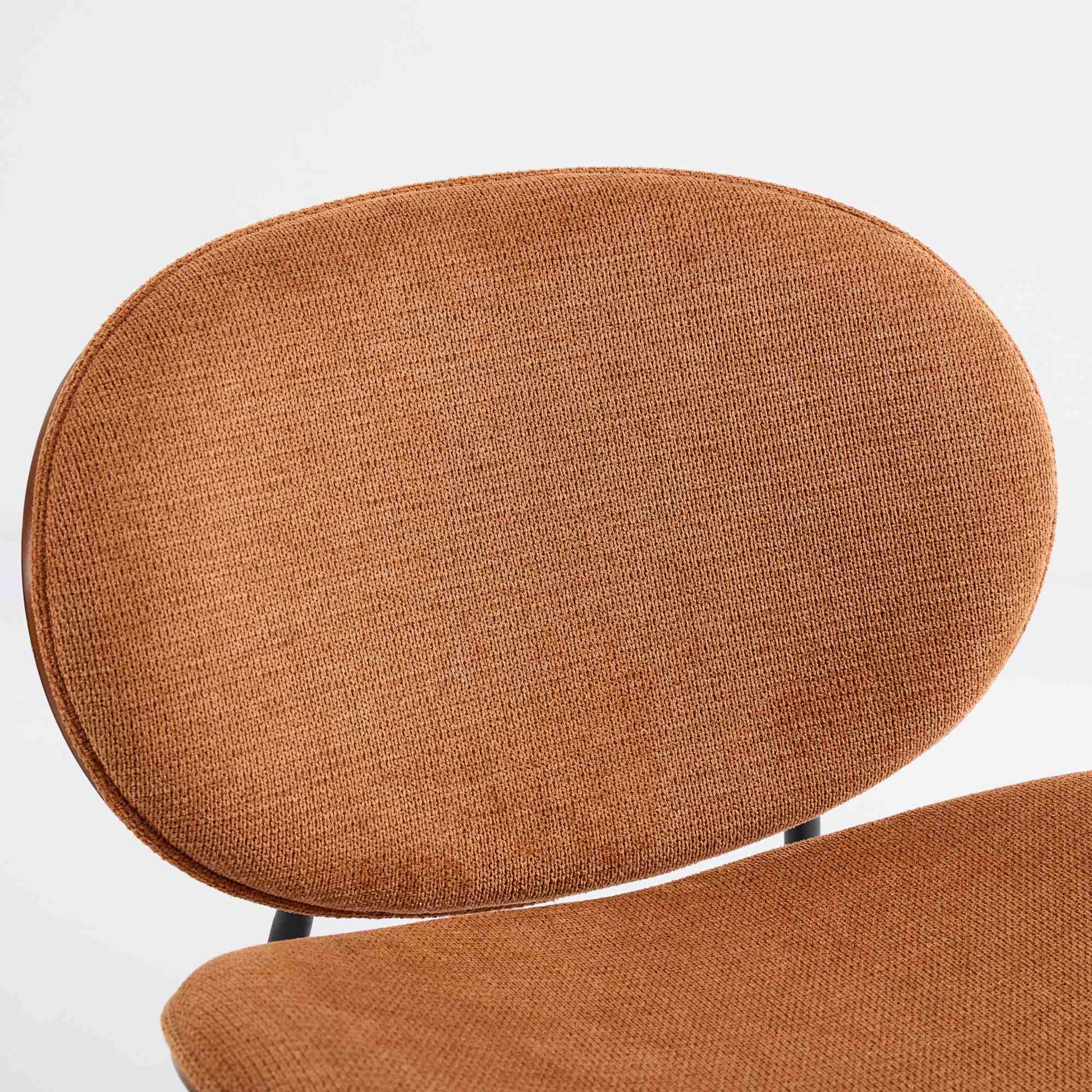 Closeup of a textured burnt orange fabric on an oval chair back