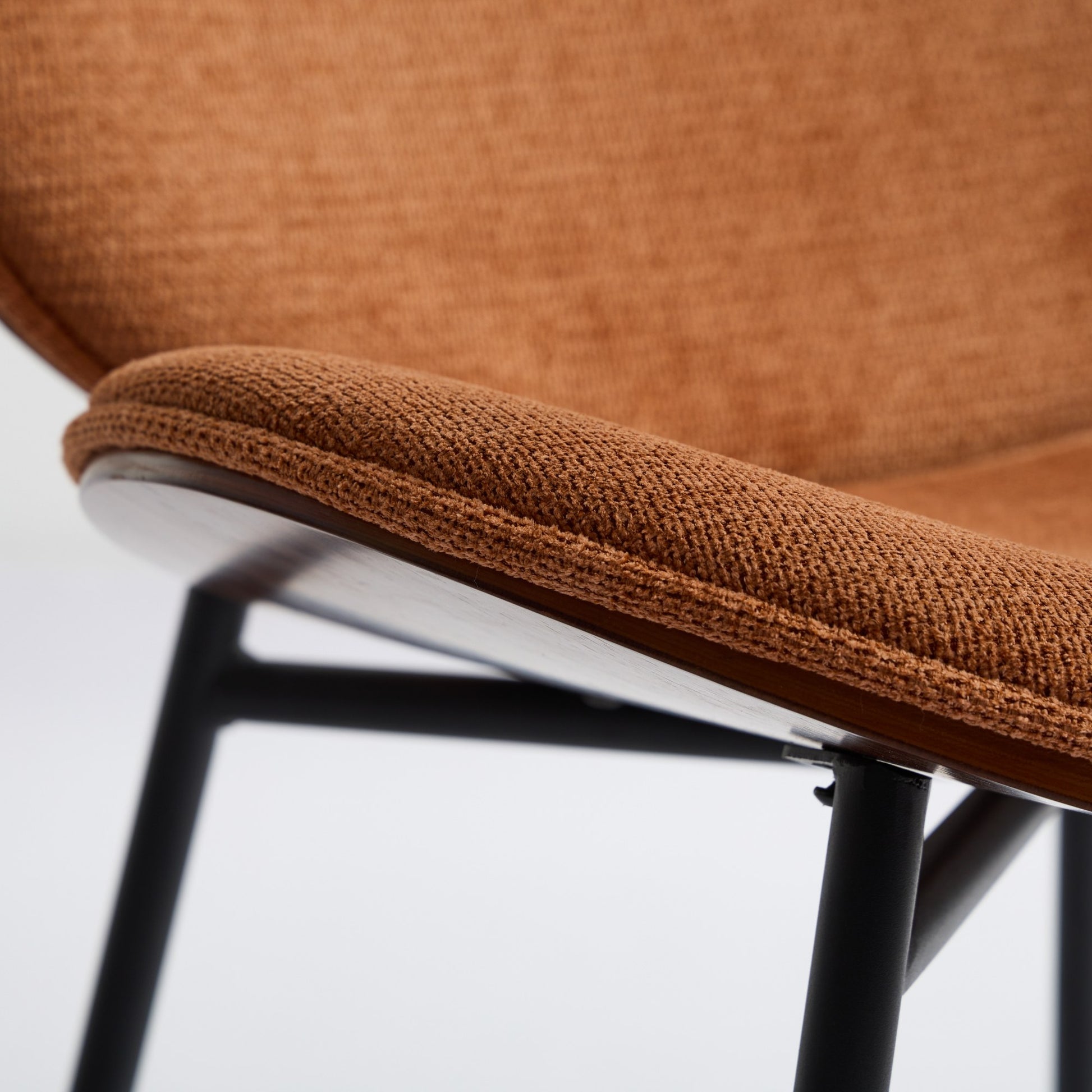 Closeup of a textured brown upholstered seat on a modern wooden chair frame