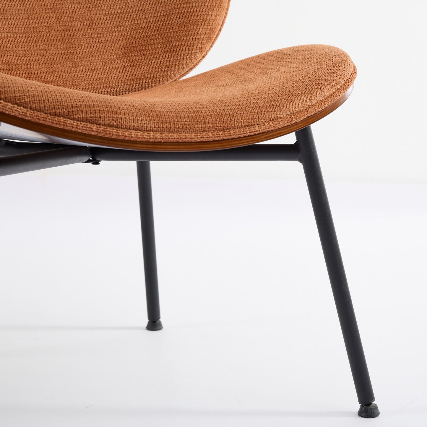 Closeup of a textured burnt orange upholstered chair seat with a dark metal frame and wood trim