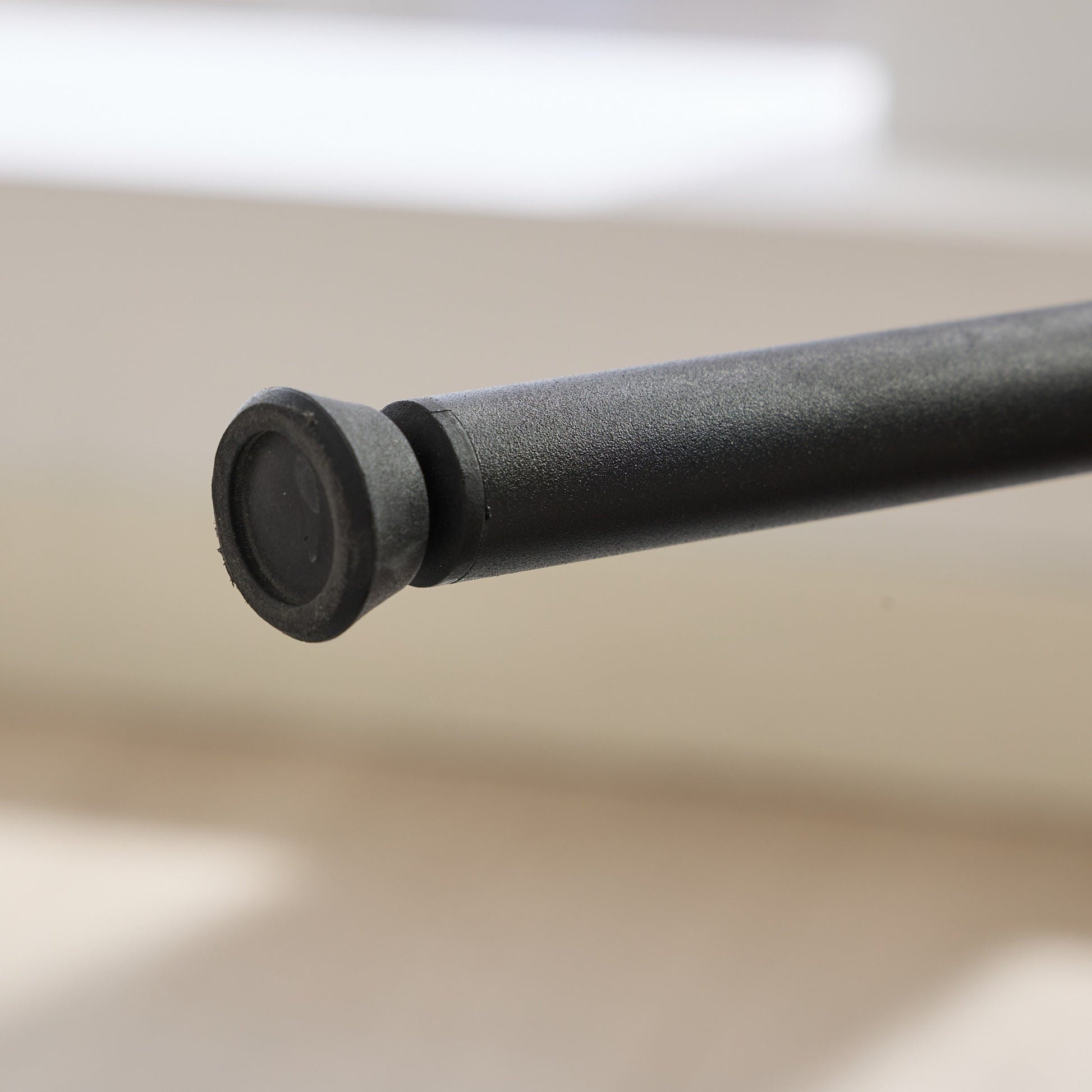 Black rubber foot cap on a textured metal tripod leg