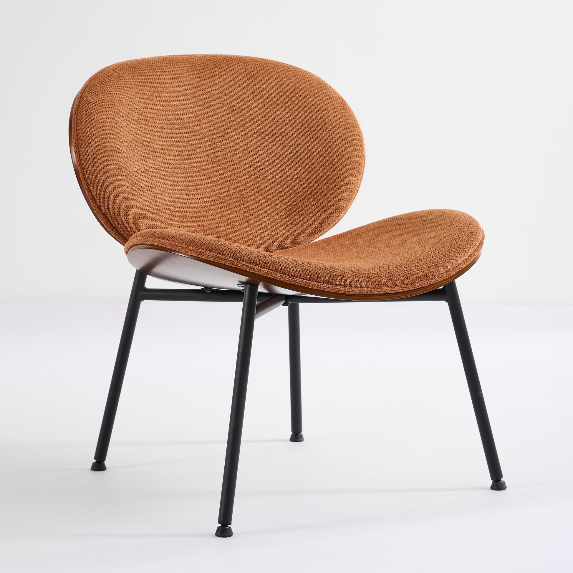Comfortable accent chair in burnt orange fabric with a walnut veneer shell and black metal legs
