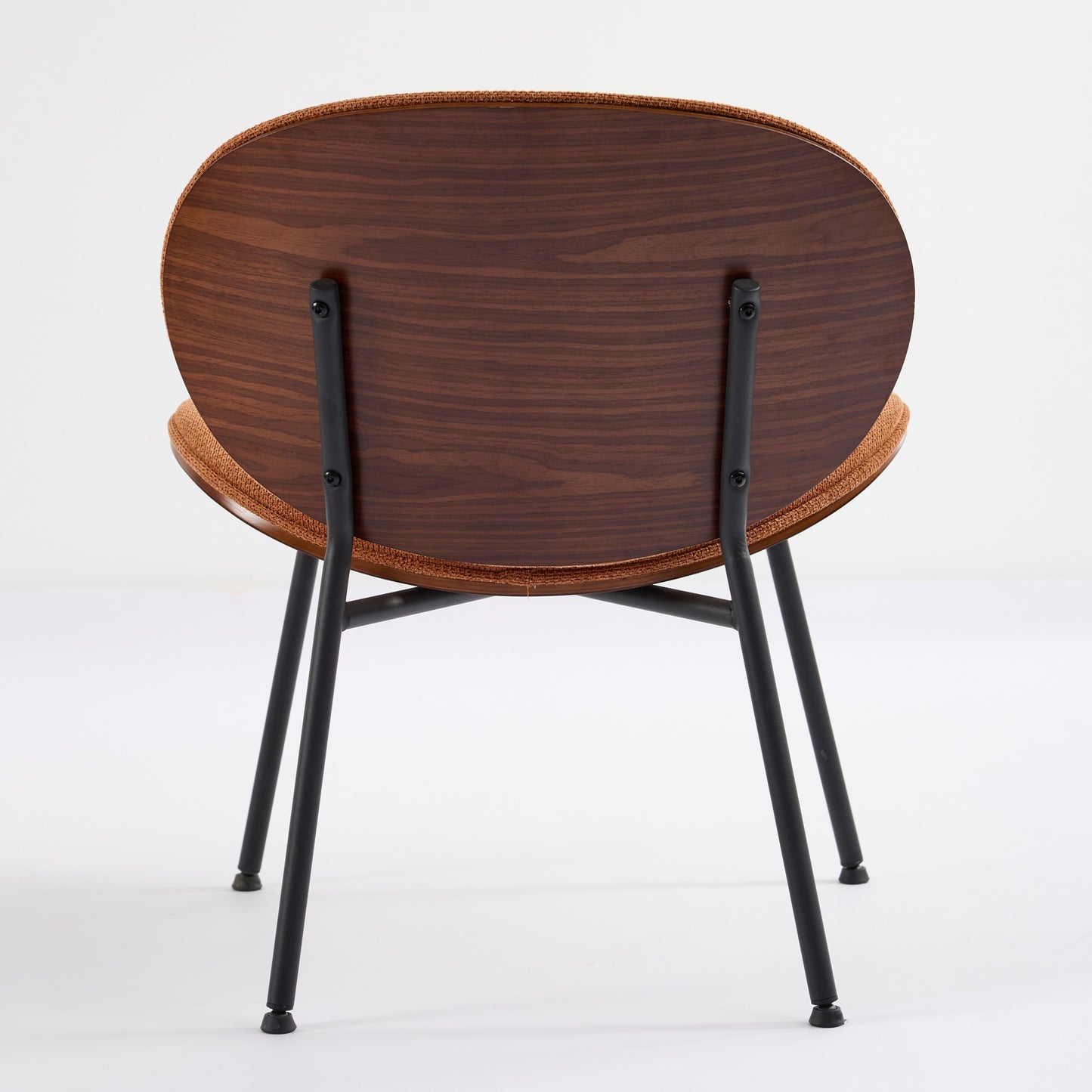 Back view of a modern dining chair with a round walnut veneer back and orange fabric seat