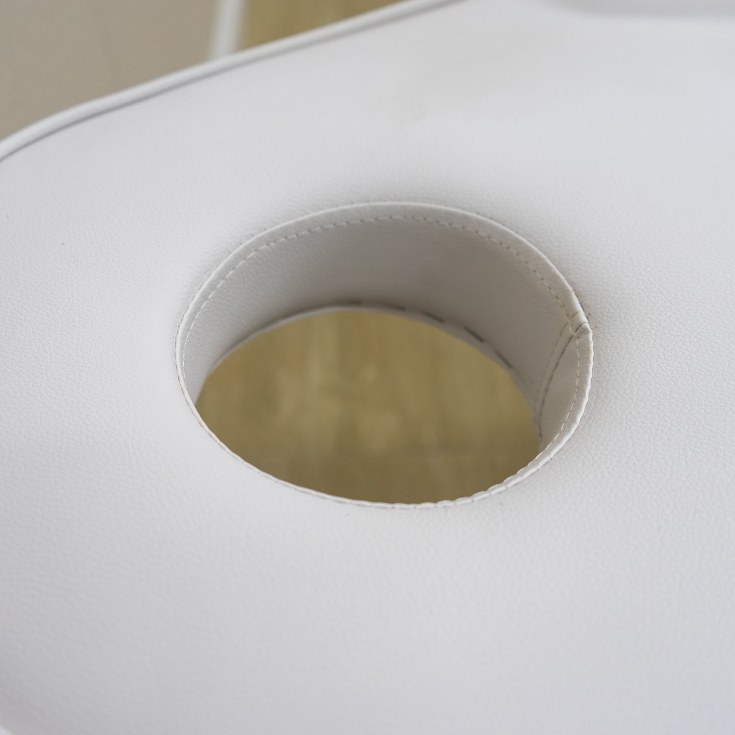 Closeup of a white vinyl massage table face cradle opening showing stitched padding