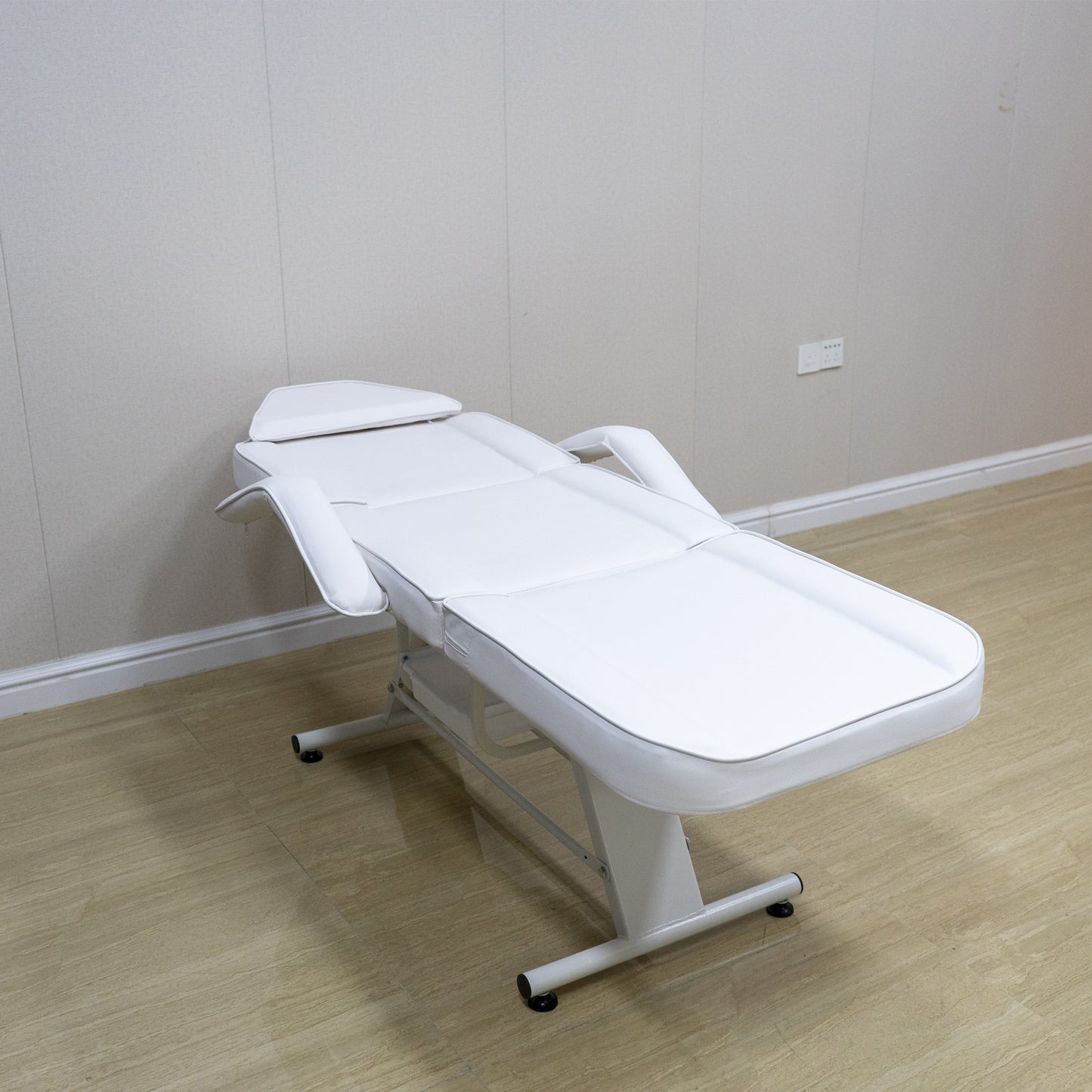 White adjustable massage bed with removable armrests and headrest ideal for spa treatments