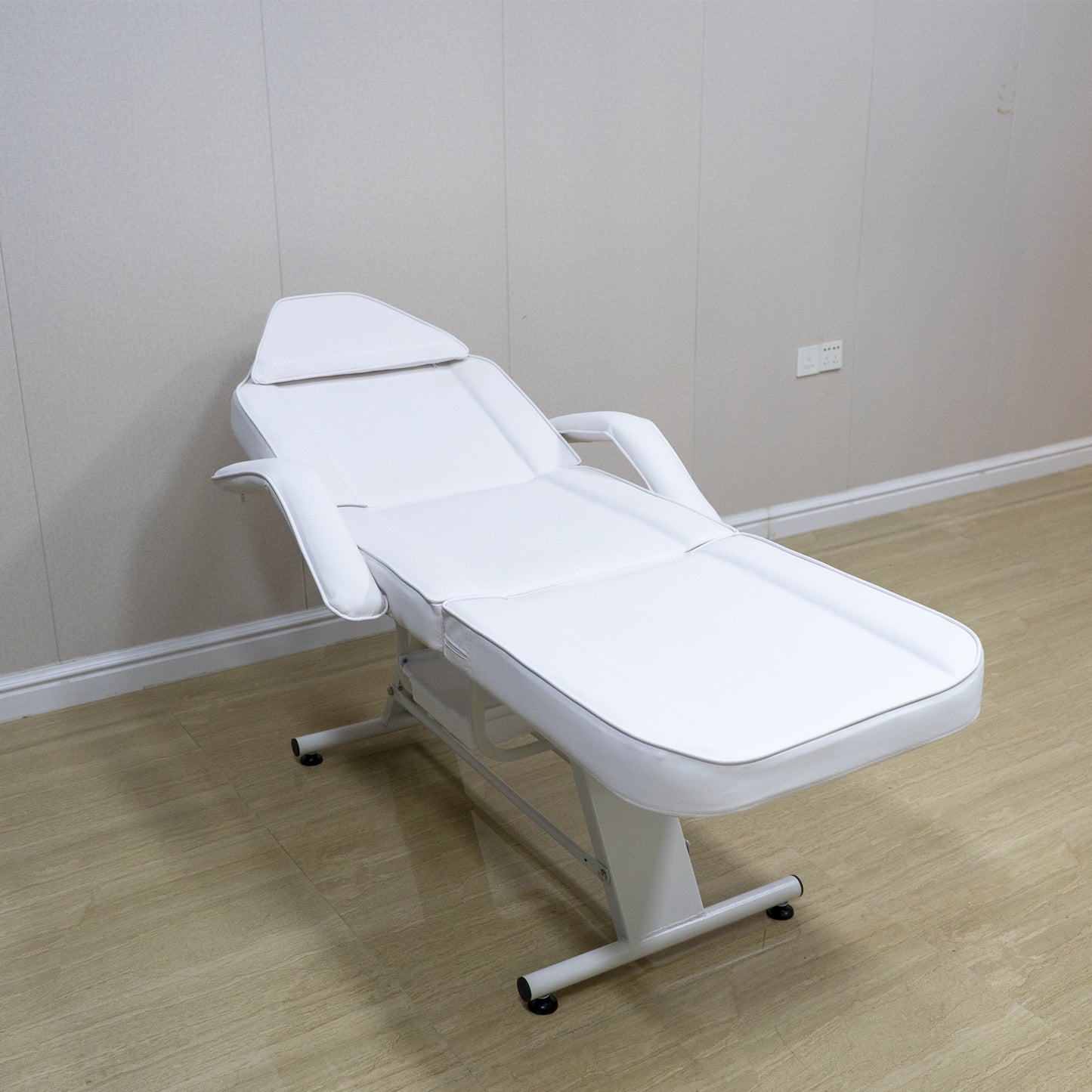 Adjustable white faux leather massage table with armrests and headrest perfect for spa treatments