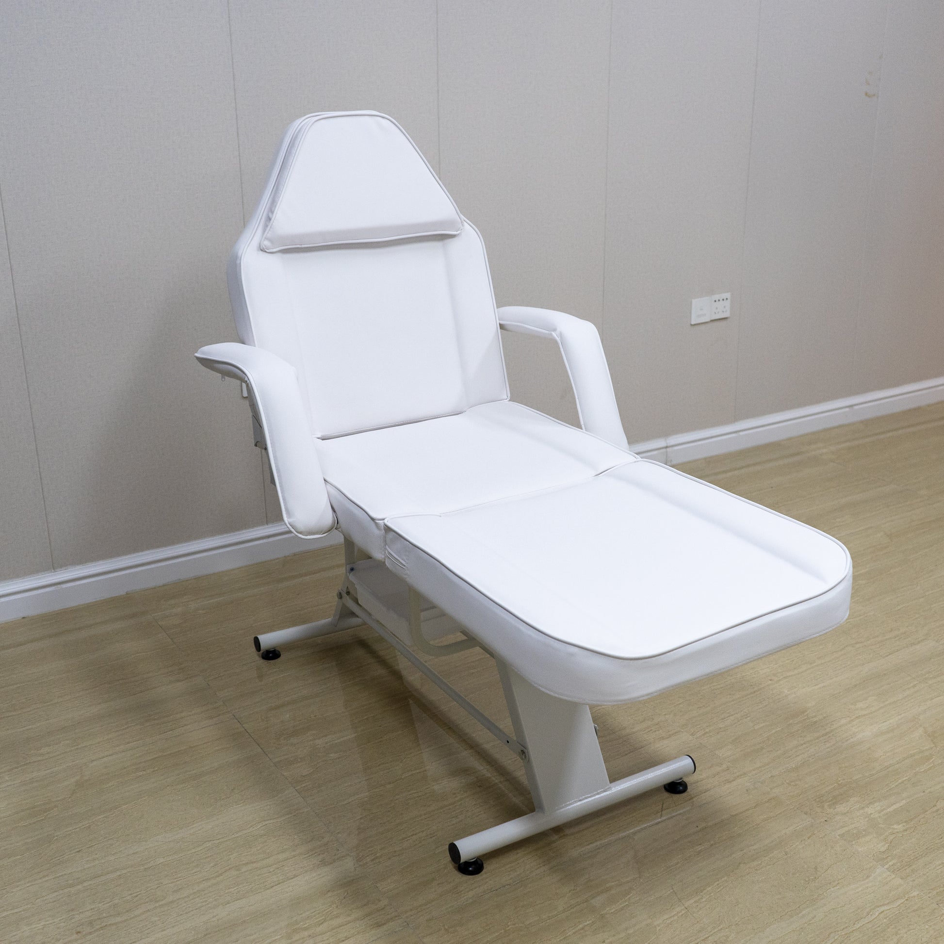 White adjustable massage bed with padded headrest and armrests for spa treatments