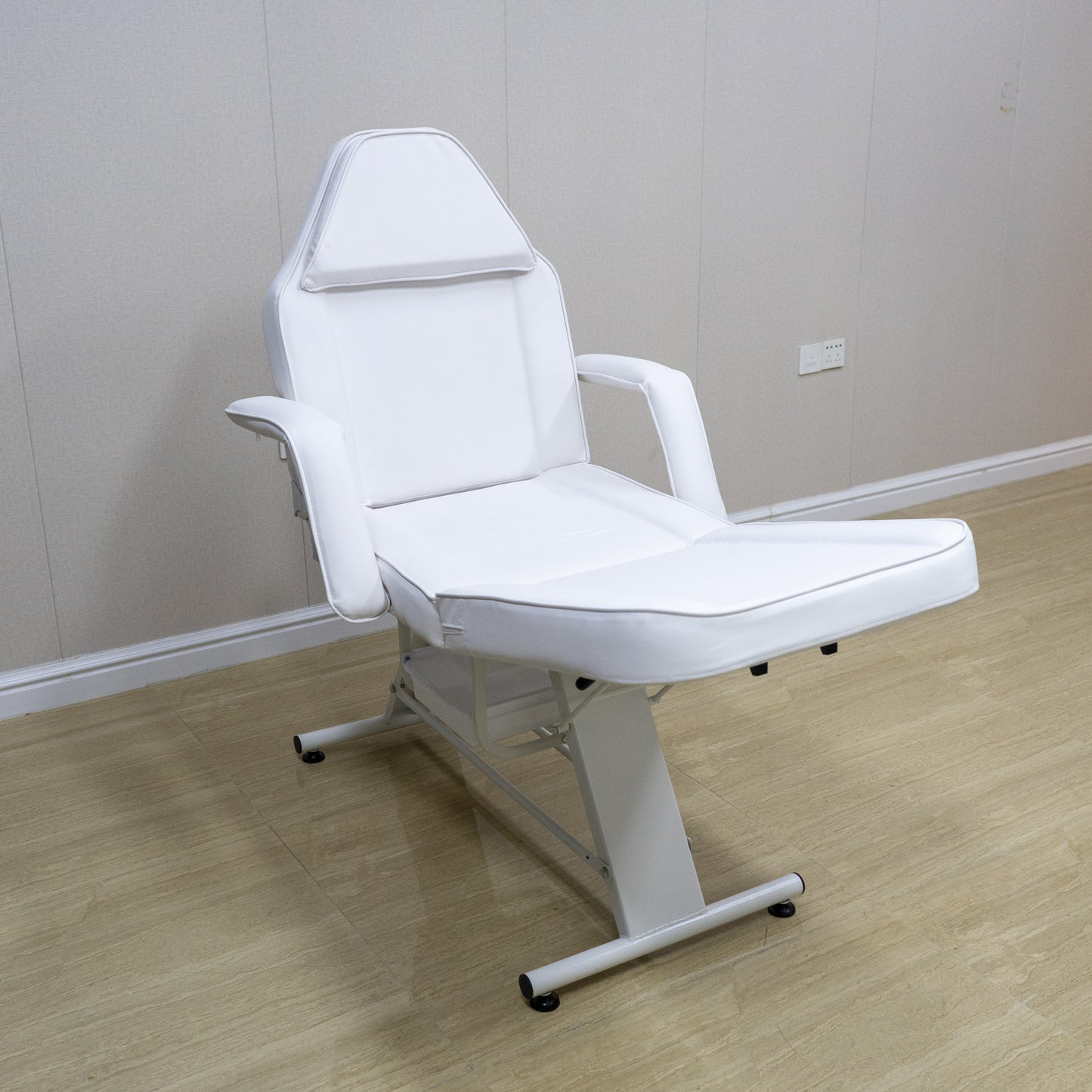 White adjustable salon chair with padded armrests and headrest for beauty treatments
