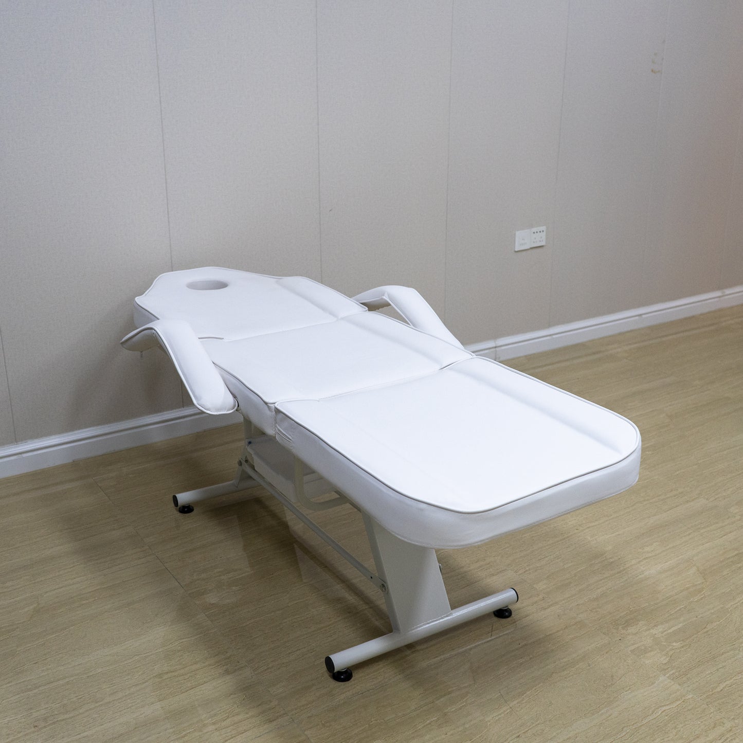 Adjustable white massage table with removable armrests and face cradle