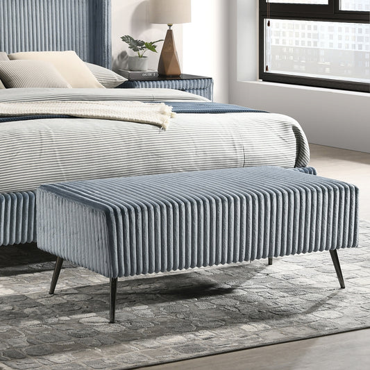 Plush blue velvet ottoman with vertical ribbing and dark metal legs