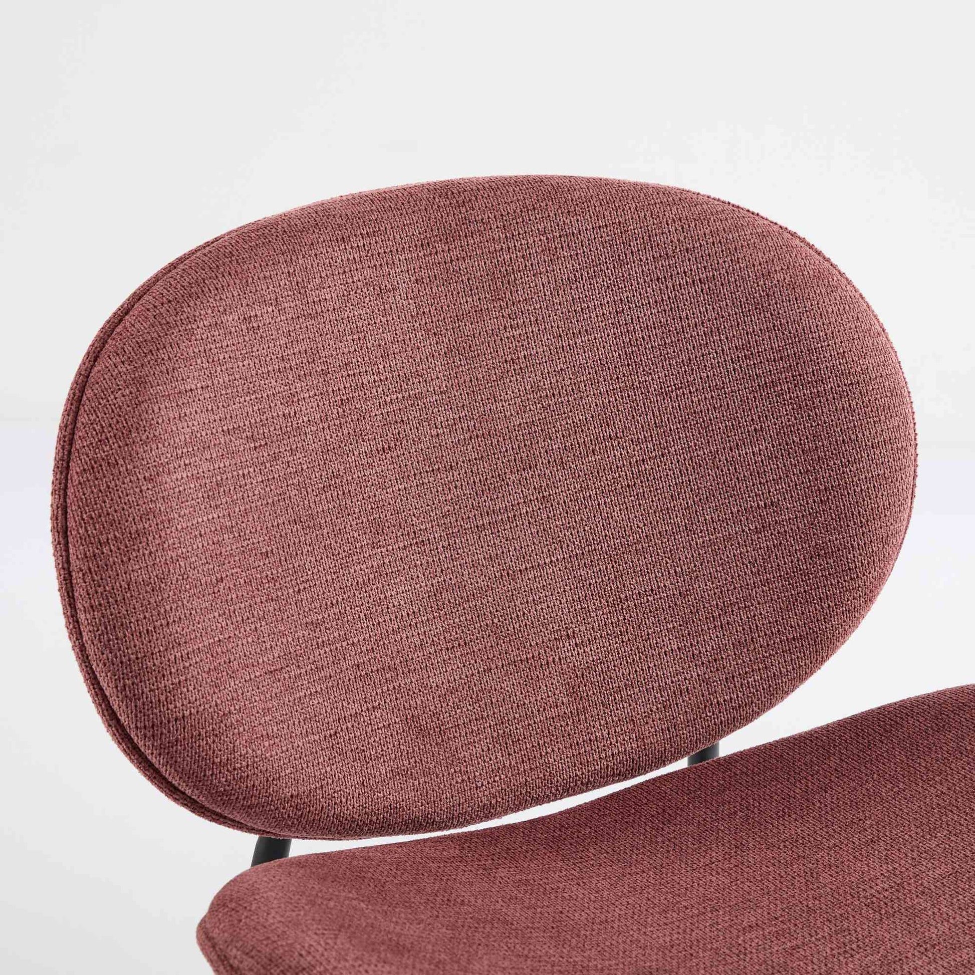 Closeup of a textured mauve fabric on a modern accent chairs oval backrest
