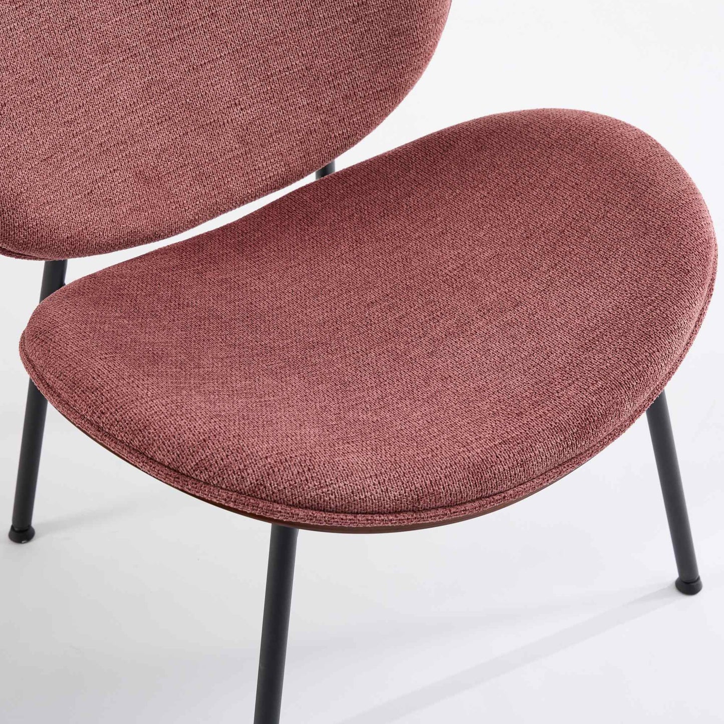 Closeup of a rosepink upholstered dining chair with black metal legs