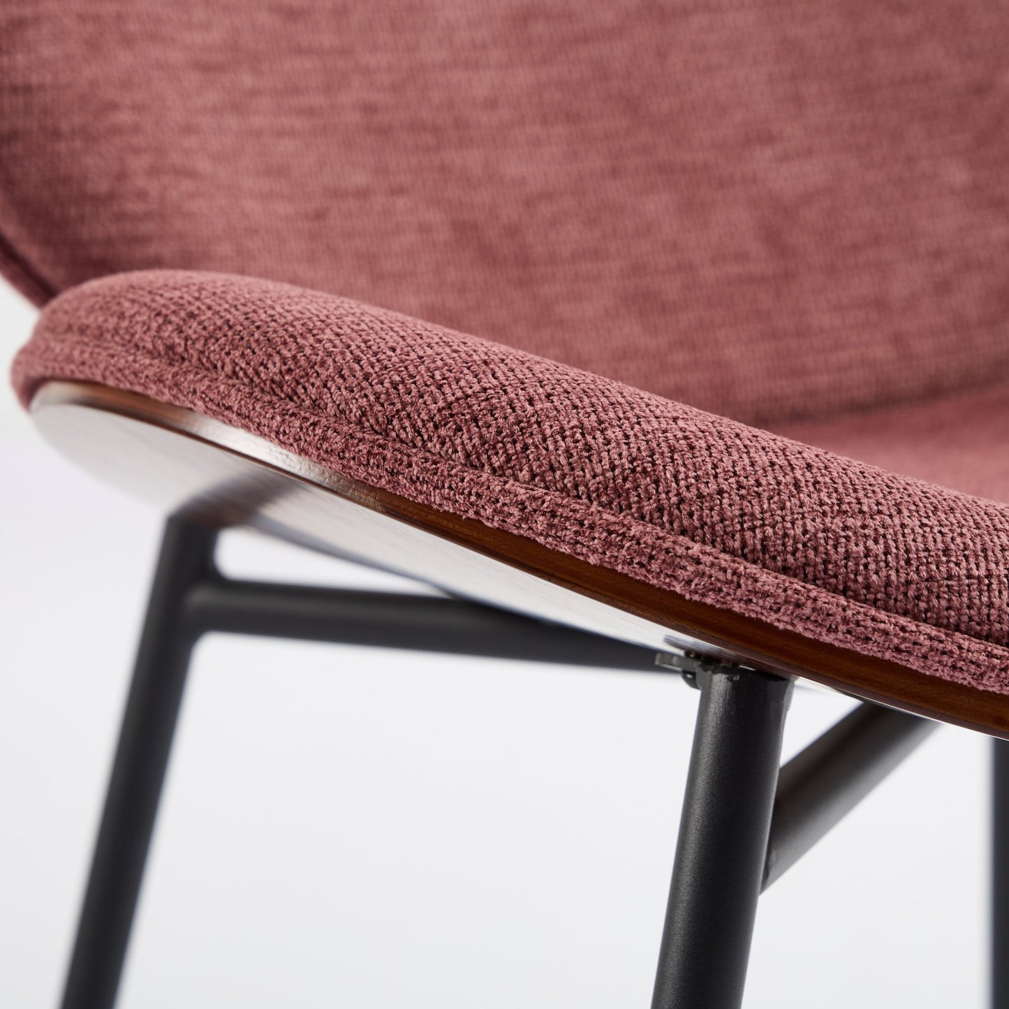 Textured rose fabric seat on a modern dining chair with dark wood trim