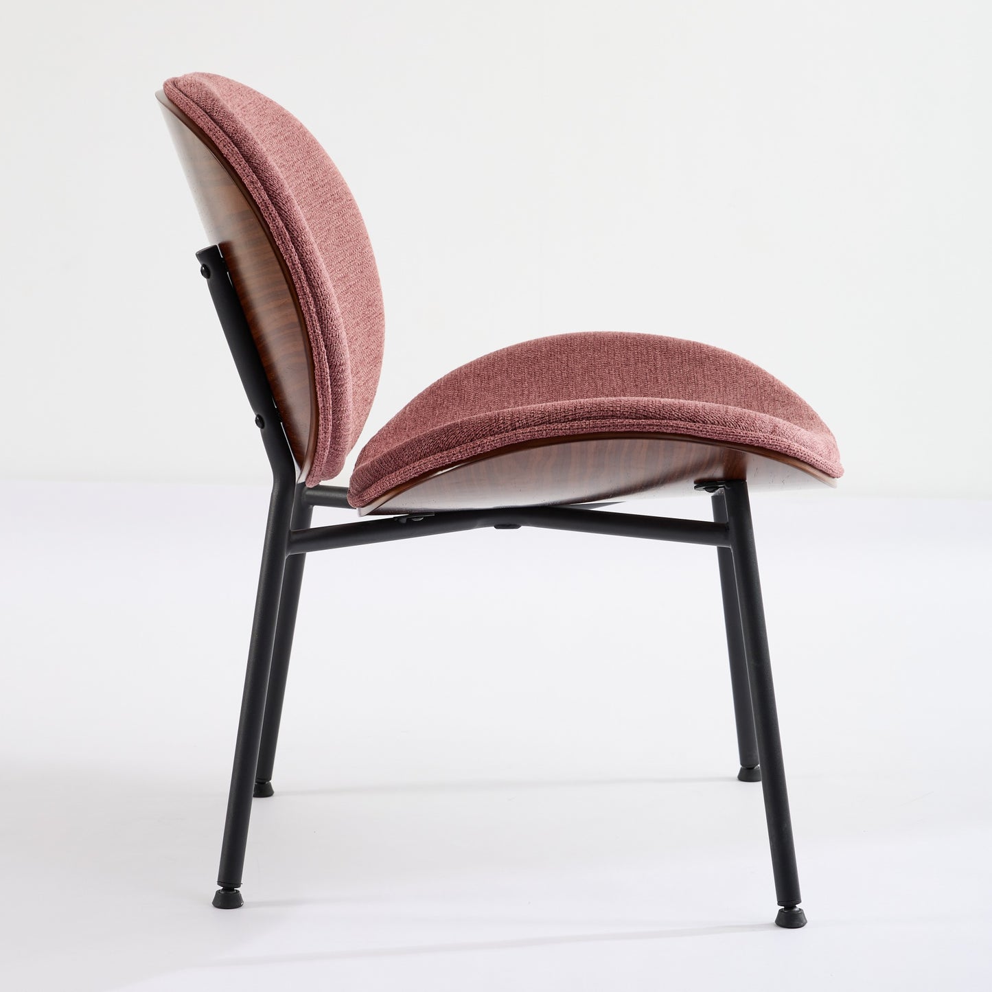 Midcentury modern chair with blush pink fabric upholstery and a molded walnut seat on black metal legs