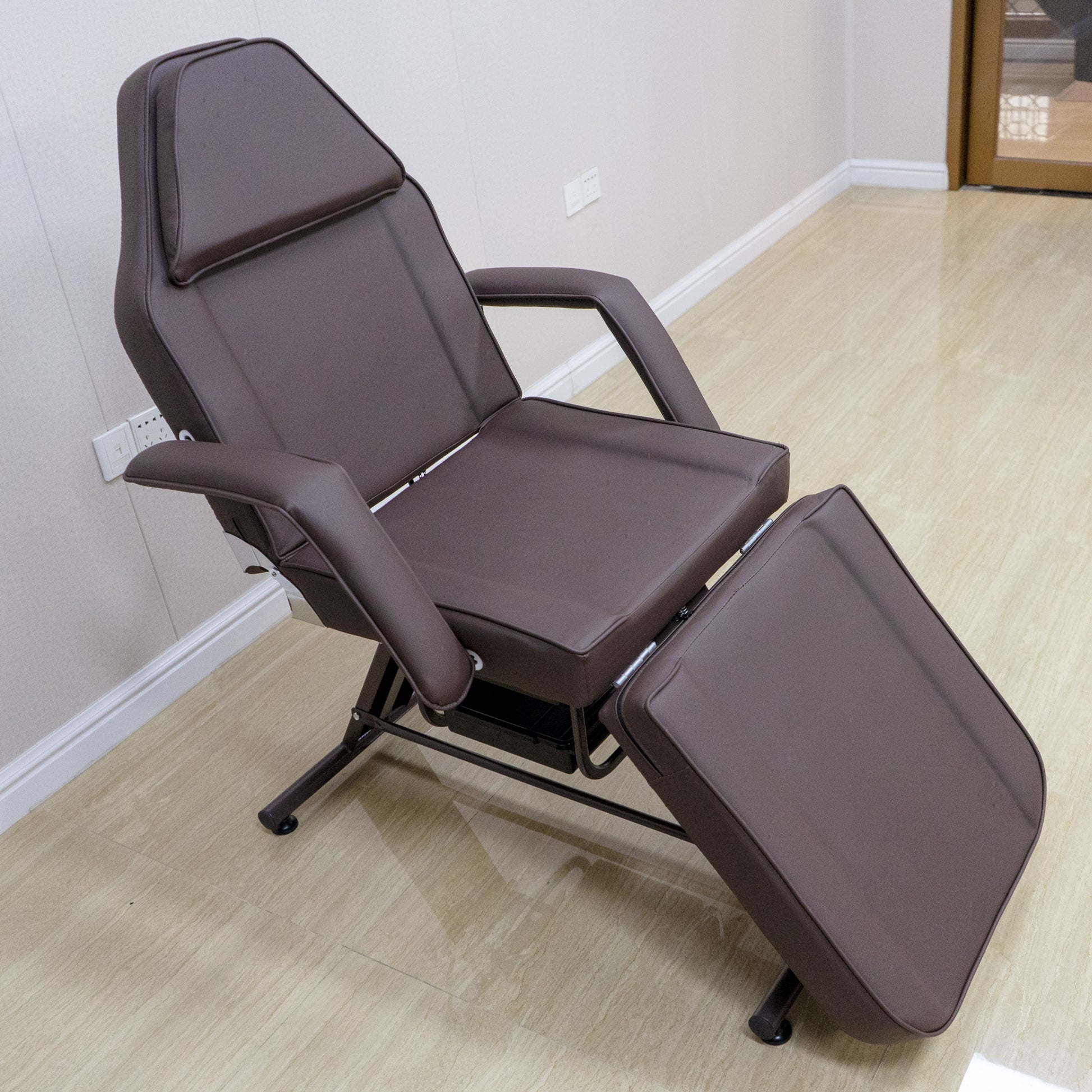Adjustable brown faux leather facial bed with reclining backrest and footrest for spa treatments