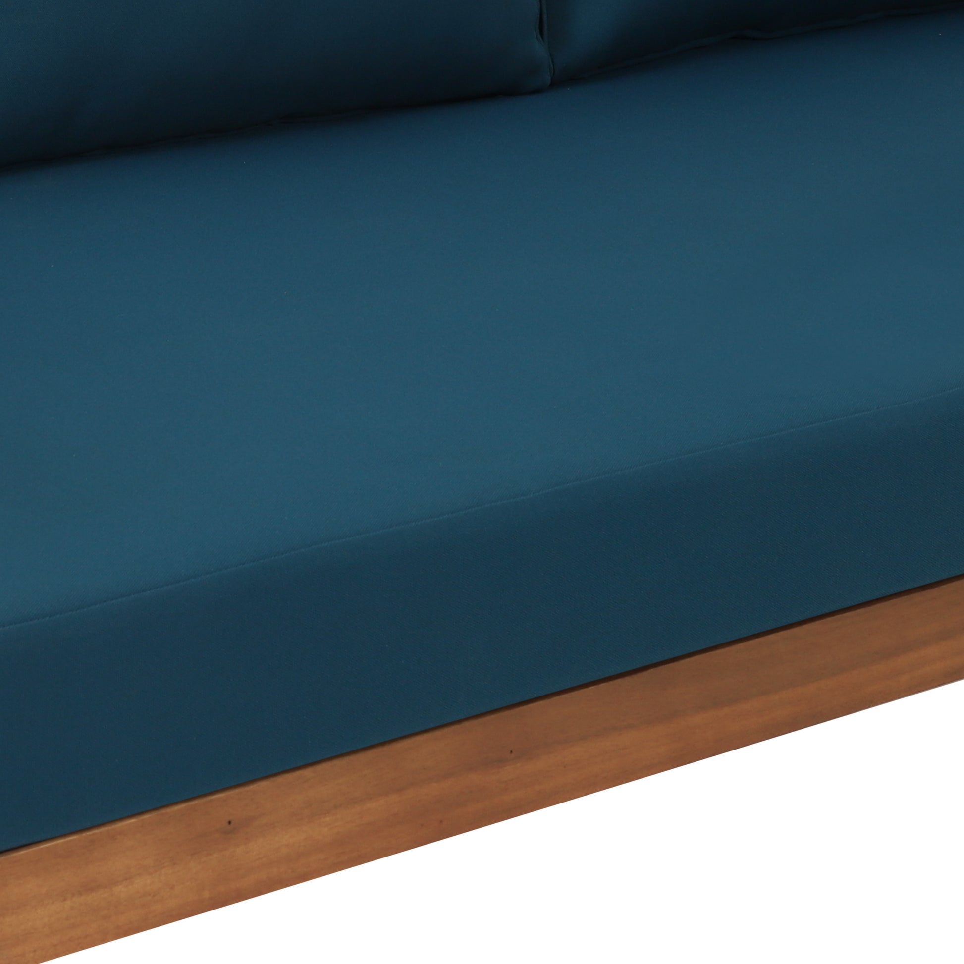 Close up of a plush teal sofa cushion with a visible seam and natural wood frame