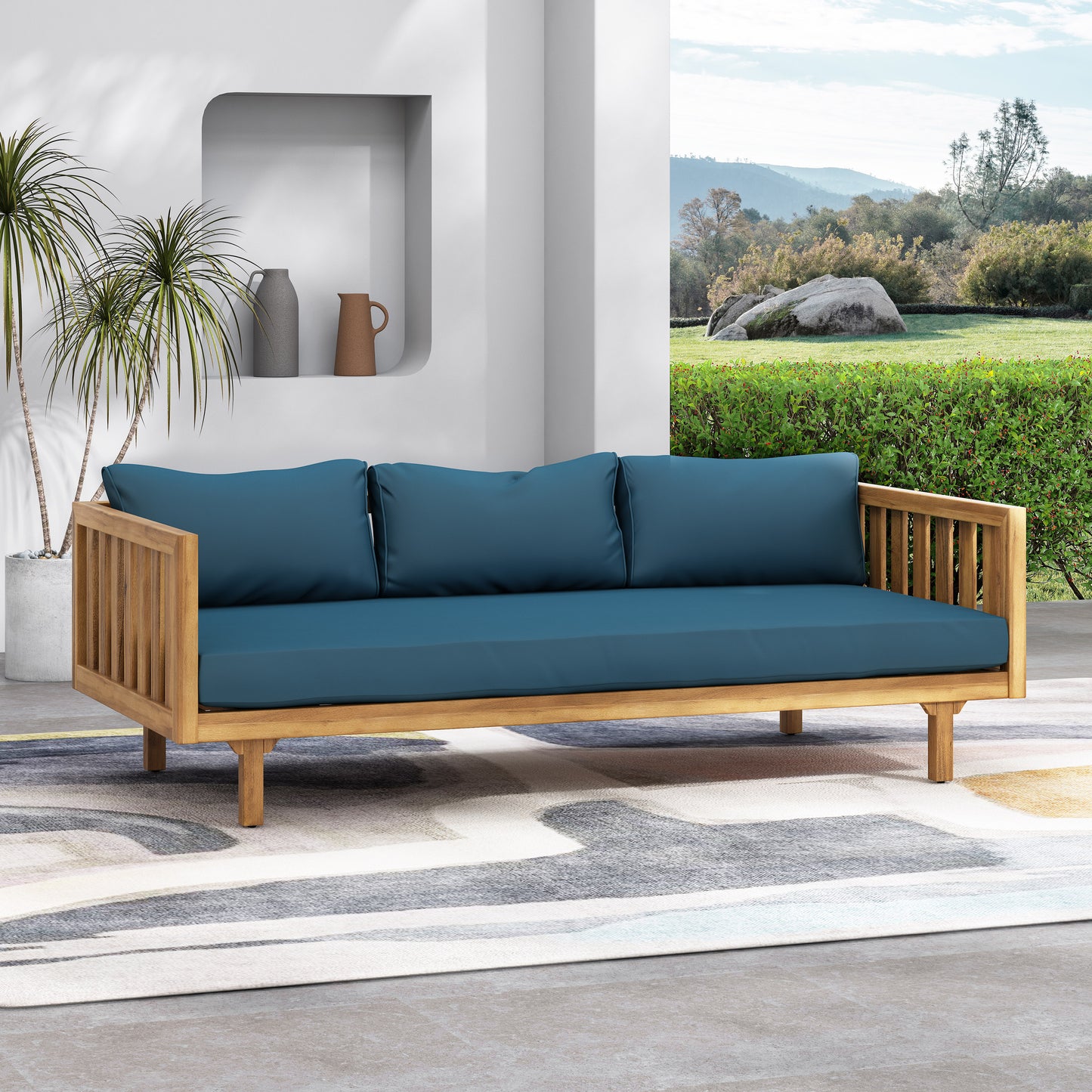 Teak wood outdoor sofa with deep blue cushions and slatted armrests perfect for patio lounging