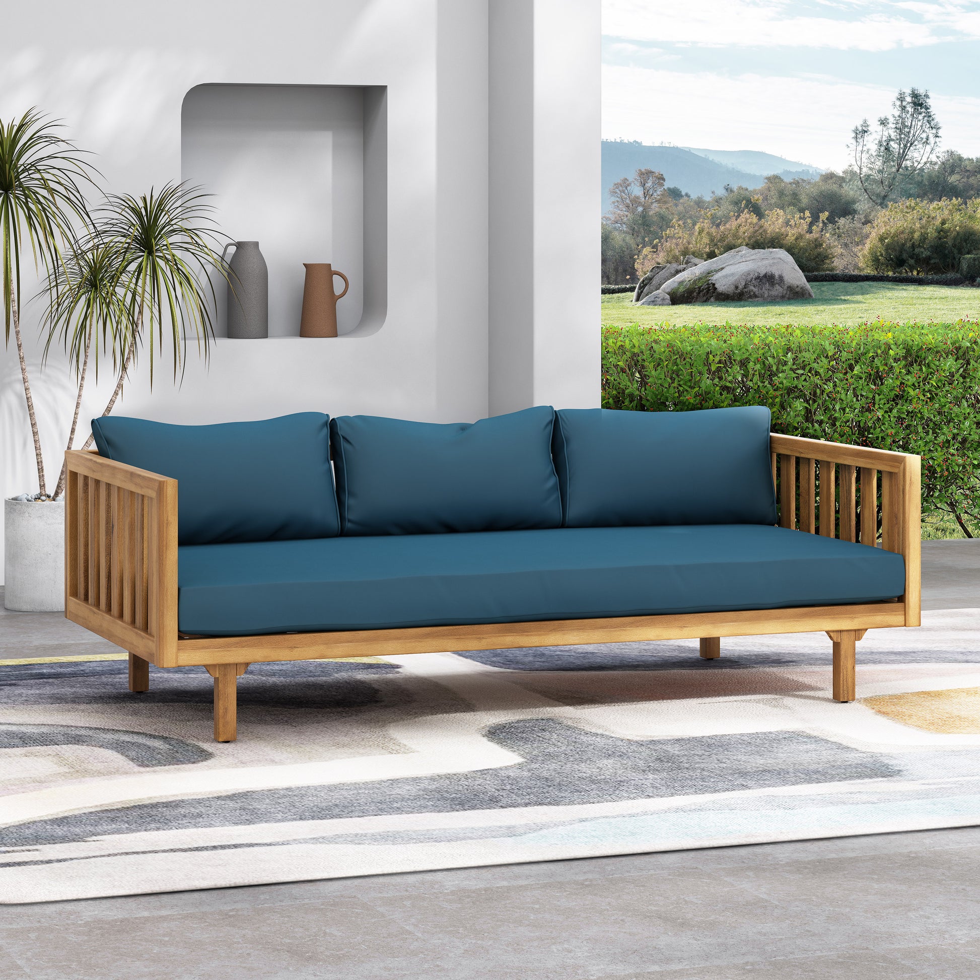 Teak wood outdoor sofa with deep blue cushions and slatted armrests perfect for patio lounging