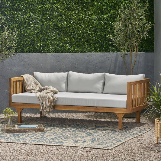 Wooden outdoor couch with light grey cushions and a woven throw