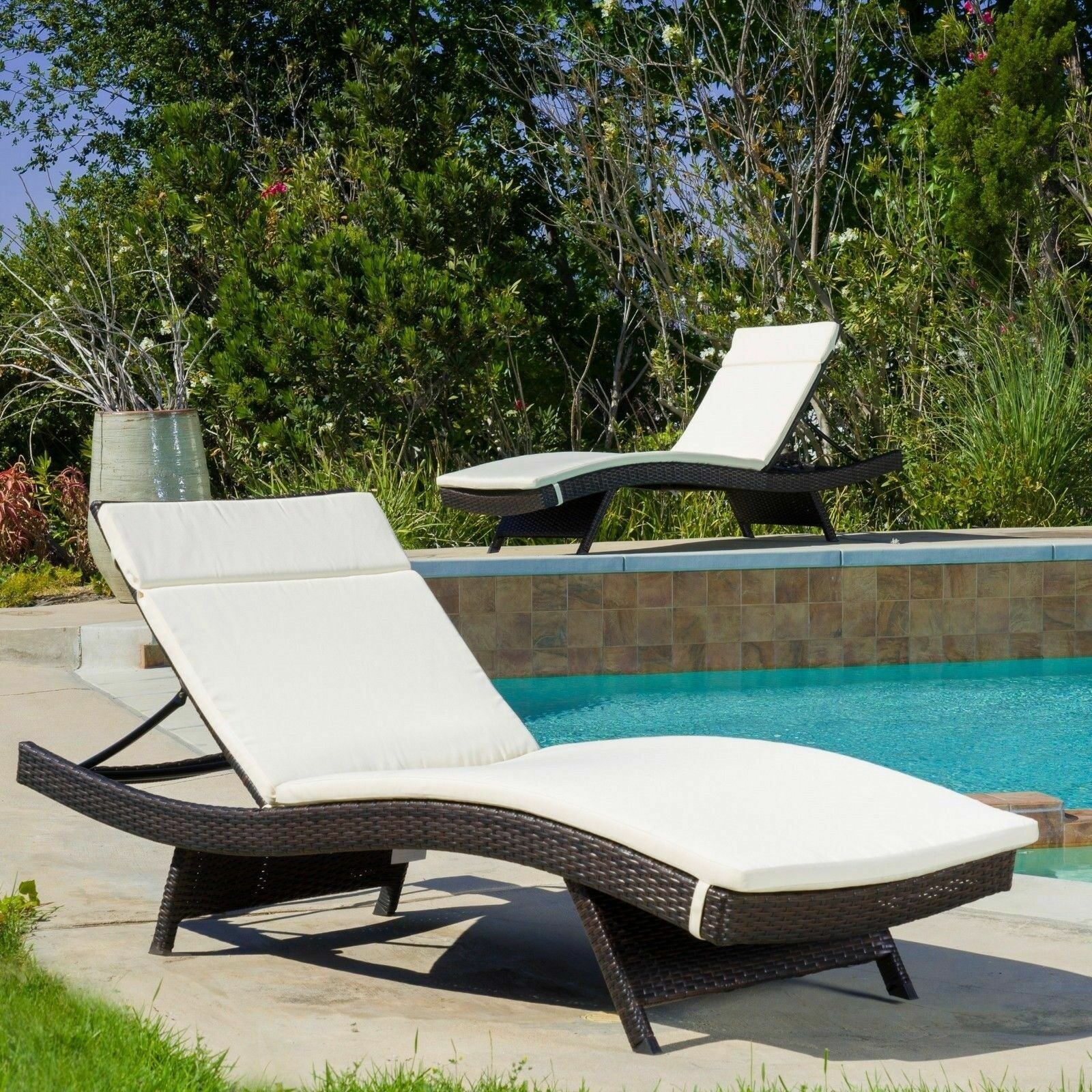 Dark brown wicker chaise lounge with cream cushions by pool