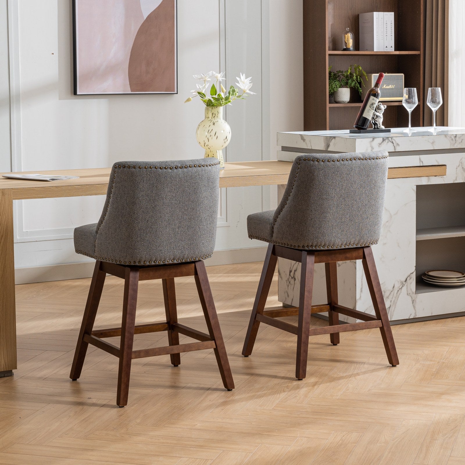 Grey upholstered swivel bar stool with nailhead trim and dark wood legs