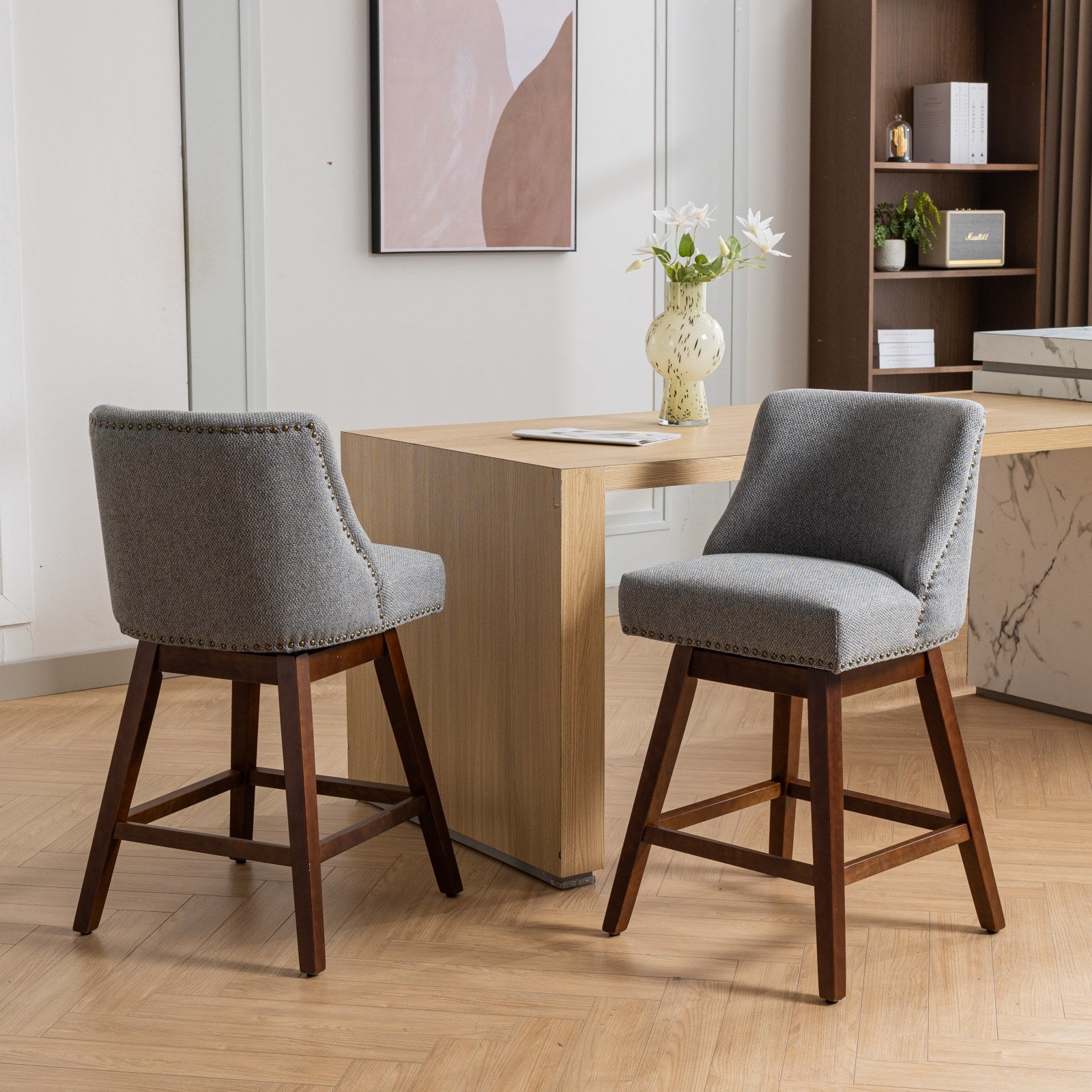 Gray upholstered swivel bar stool with nailhead trim and dark wood legs