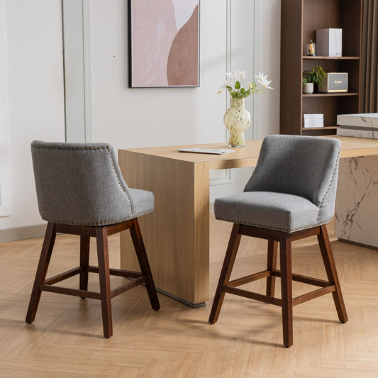 Gray upholstered swivel bar stool with nailhead trim and dark wood legs