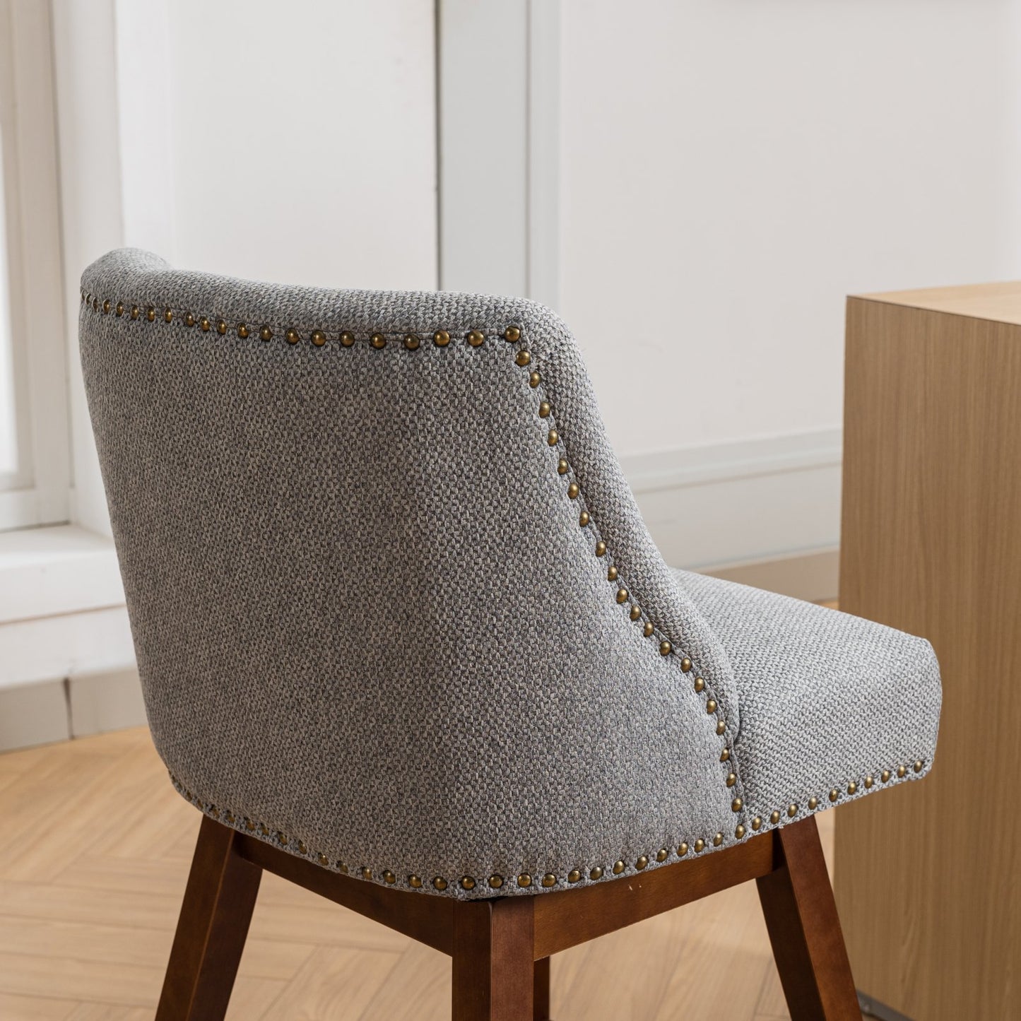 Gray textured fabric armchair with decorative brass nailhead trim and wooden legs