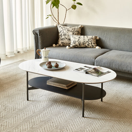 Oval marble coffee table with black metal frame featuring books and a moka pot