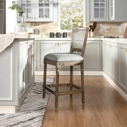 Distressed wood bar stool with woven cane back and upholstered gray seat