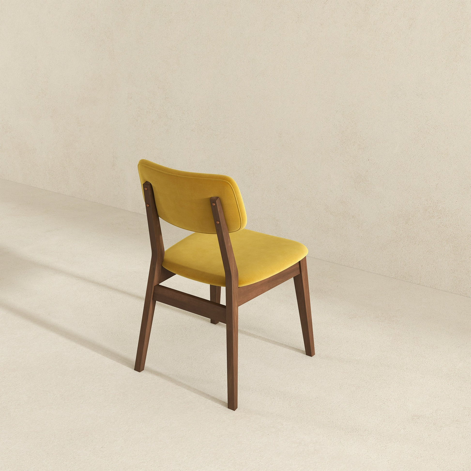 Back view of yellow velvet dining chair with dark wood frame