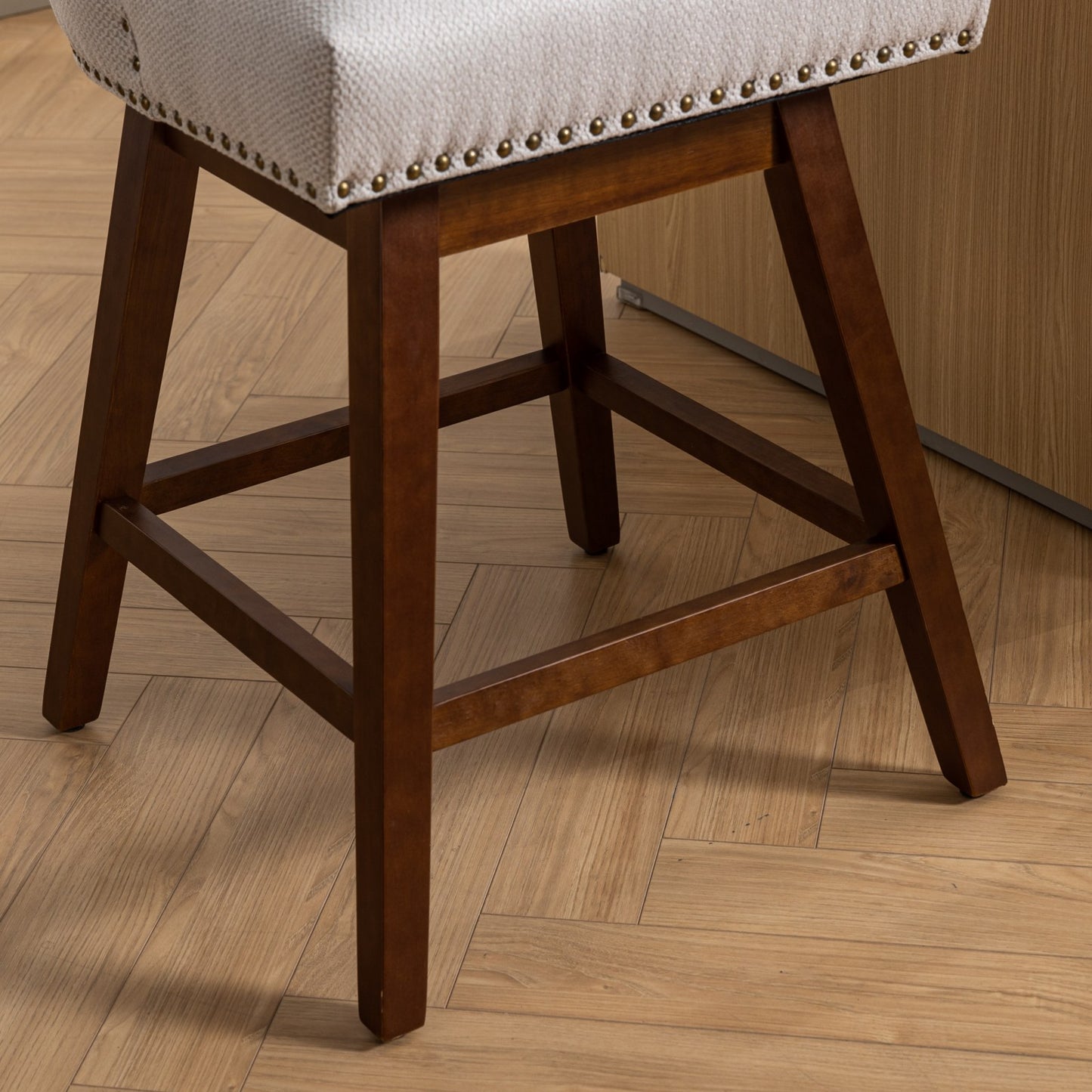 Upholstered bar stool with a neutral textured seat and dark wood legs featuring decorative nailhead trim