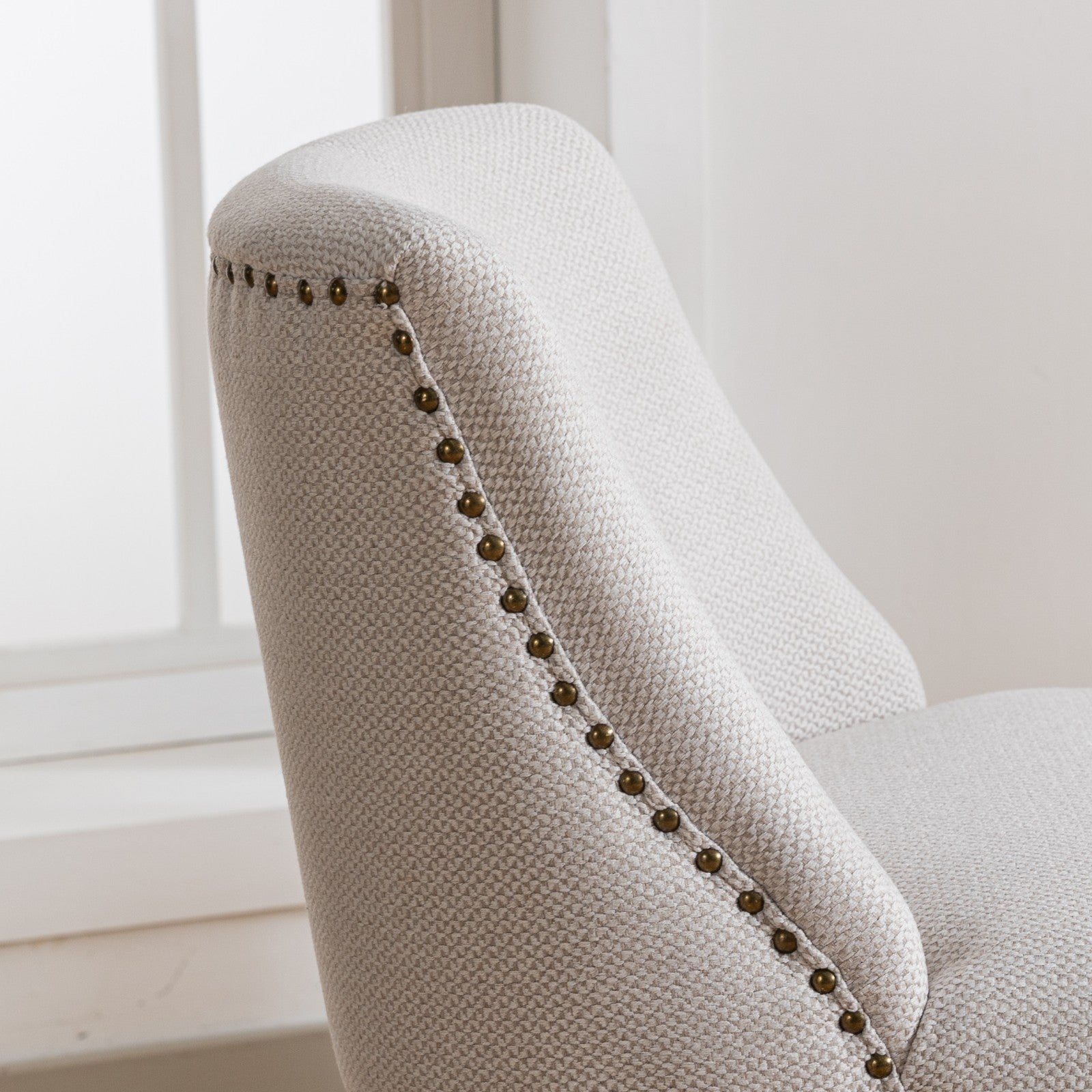 Cream textured armchair with antique brass nailhead trim detailing