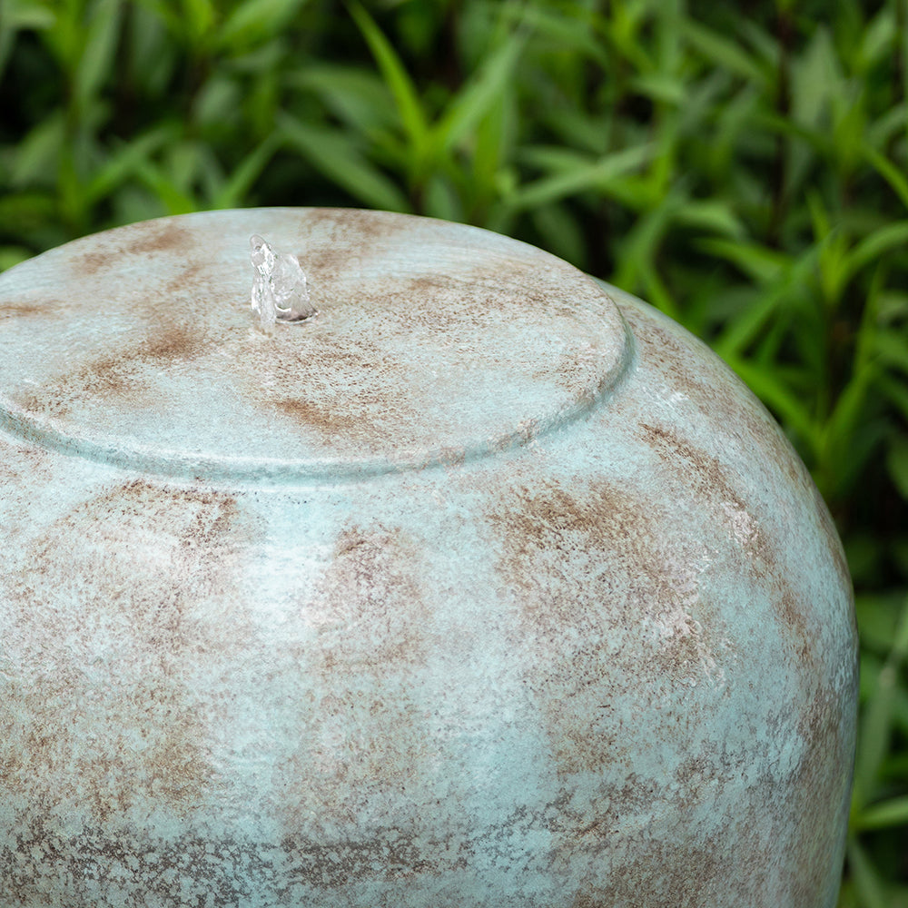 Closeup of a weathered blue garden fountain top with a small water stream perfect for tranquil outdoor spaces