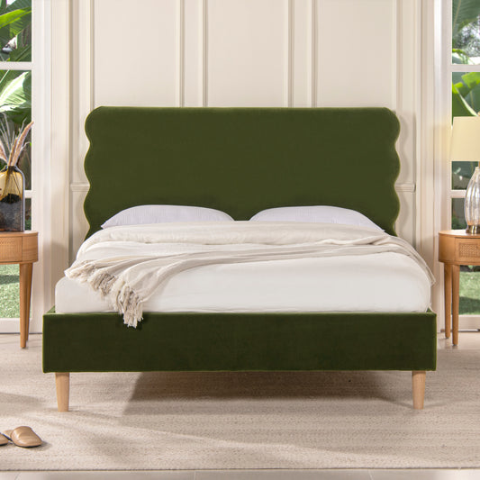 Emerald green velvet platform bed with scalloped headboard and wooden legs