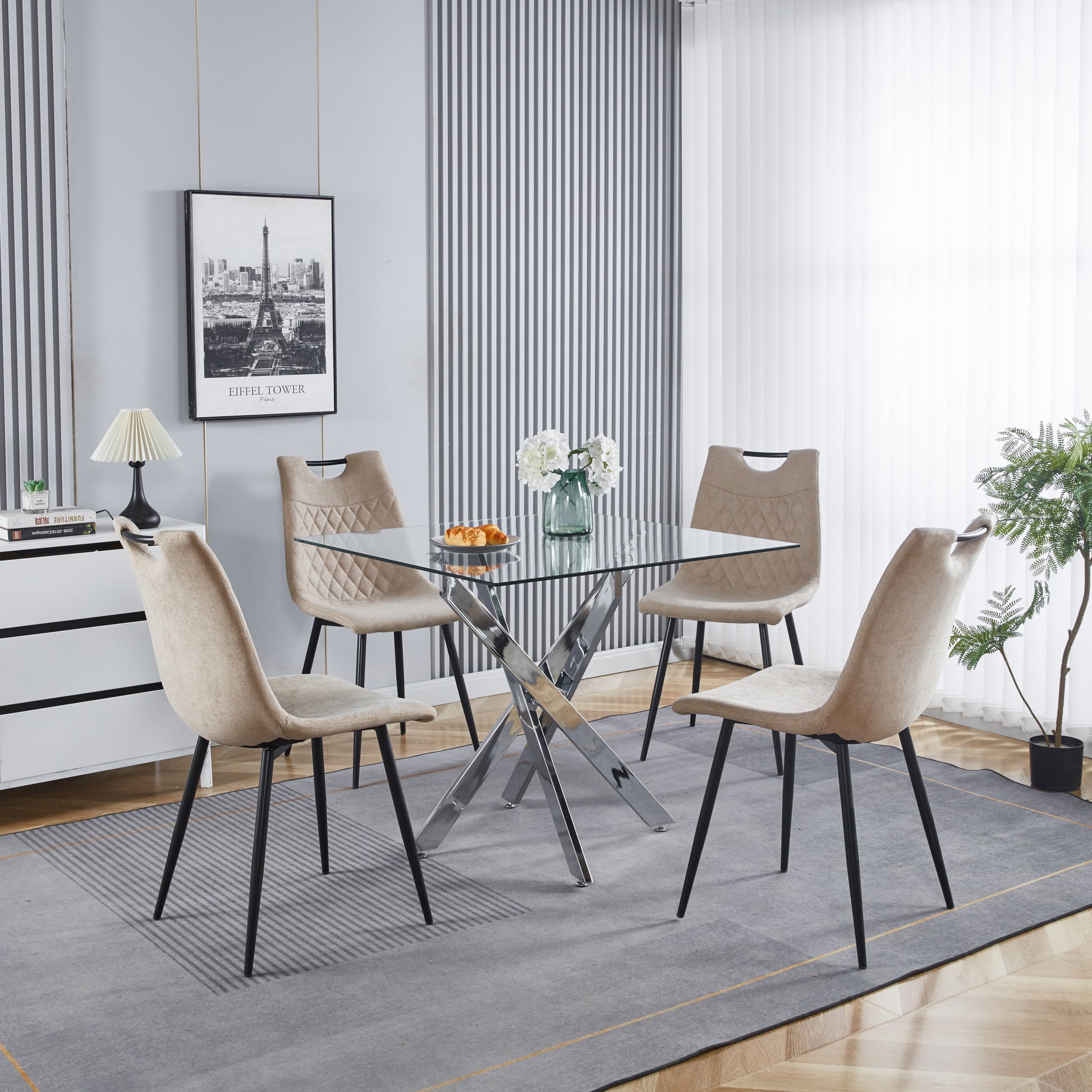 Glass top dining table with chrome base and four beige upholstered chairs